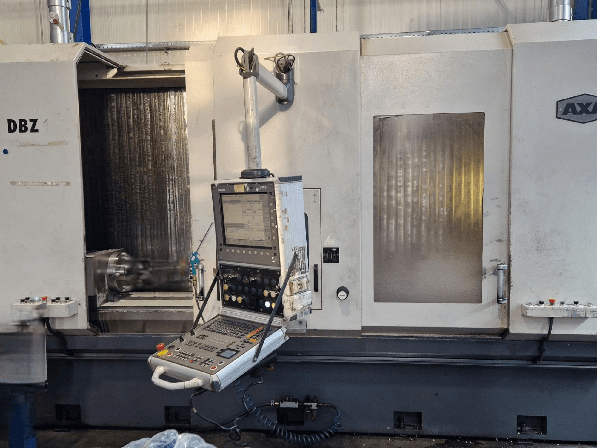 Pionowe centrum obróbcze AXA DBZ pokazane z przodu pod kątem, z panelem sterowania i widocznym obszarem narzędzi skrawających.