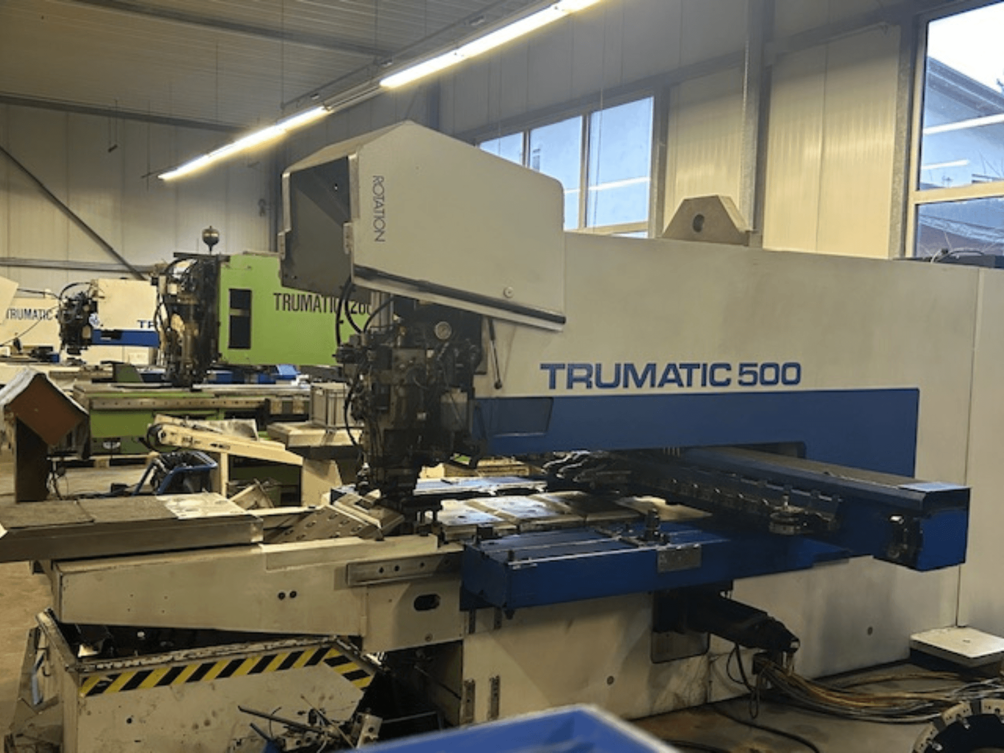 Wykrawarka CNC TRUMPF TRUMATIC 500, widok z przodu, z panelem sterowania i częściami mechanicznymi. Warsztat przemysłowy.