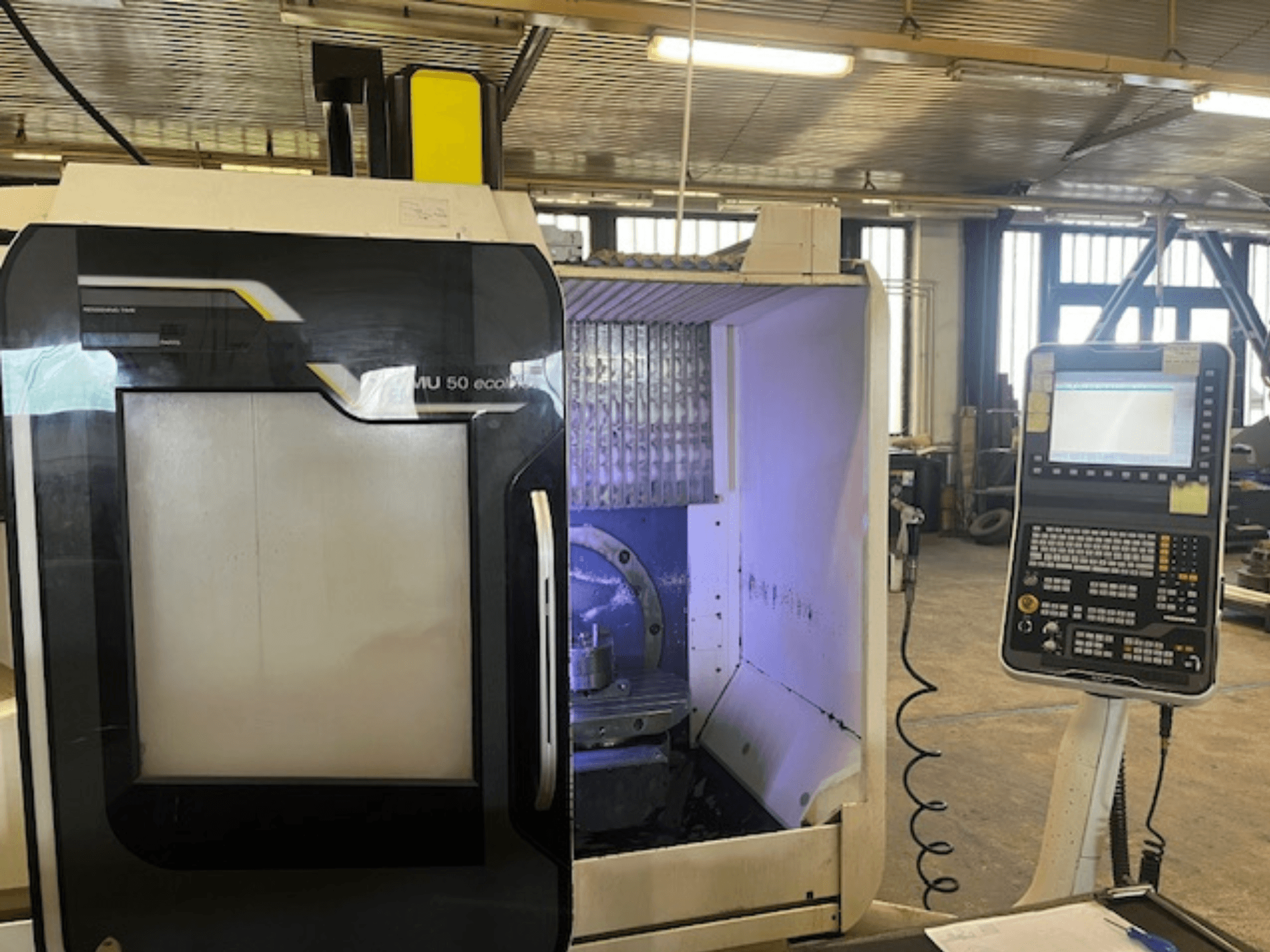 Frezarka DMU 50 eco widok z przodu z panelem sterowania, wyświetlającym uchwyt narzędziowy i obszar roboczy.