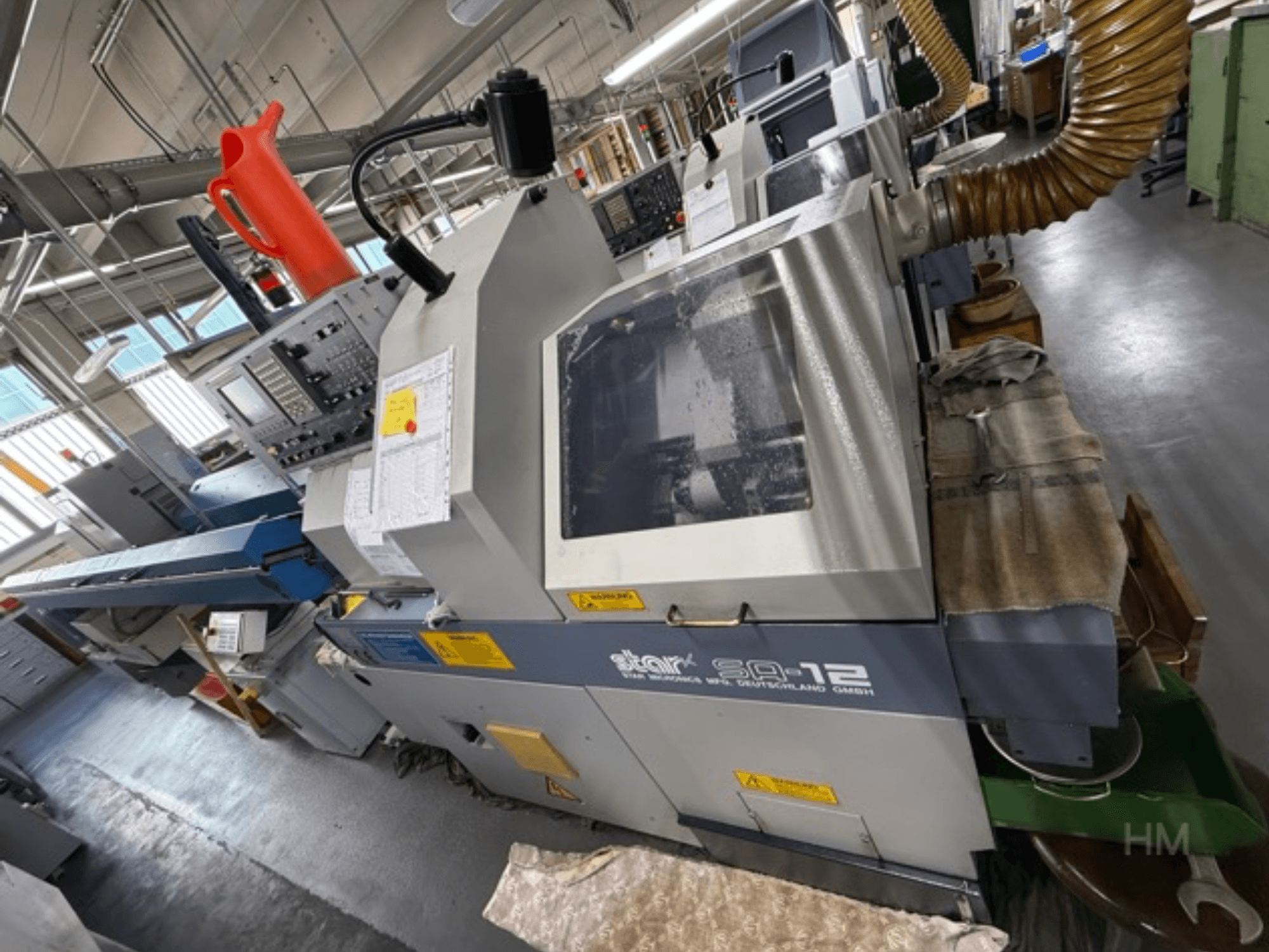 Centrum obróbcze Star SQ-12, widok z boku z widocznym panelem sterowania, zbiornikiem chłodziwa i wężem odpylającym.