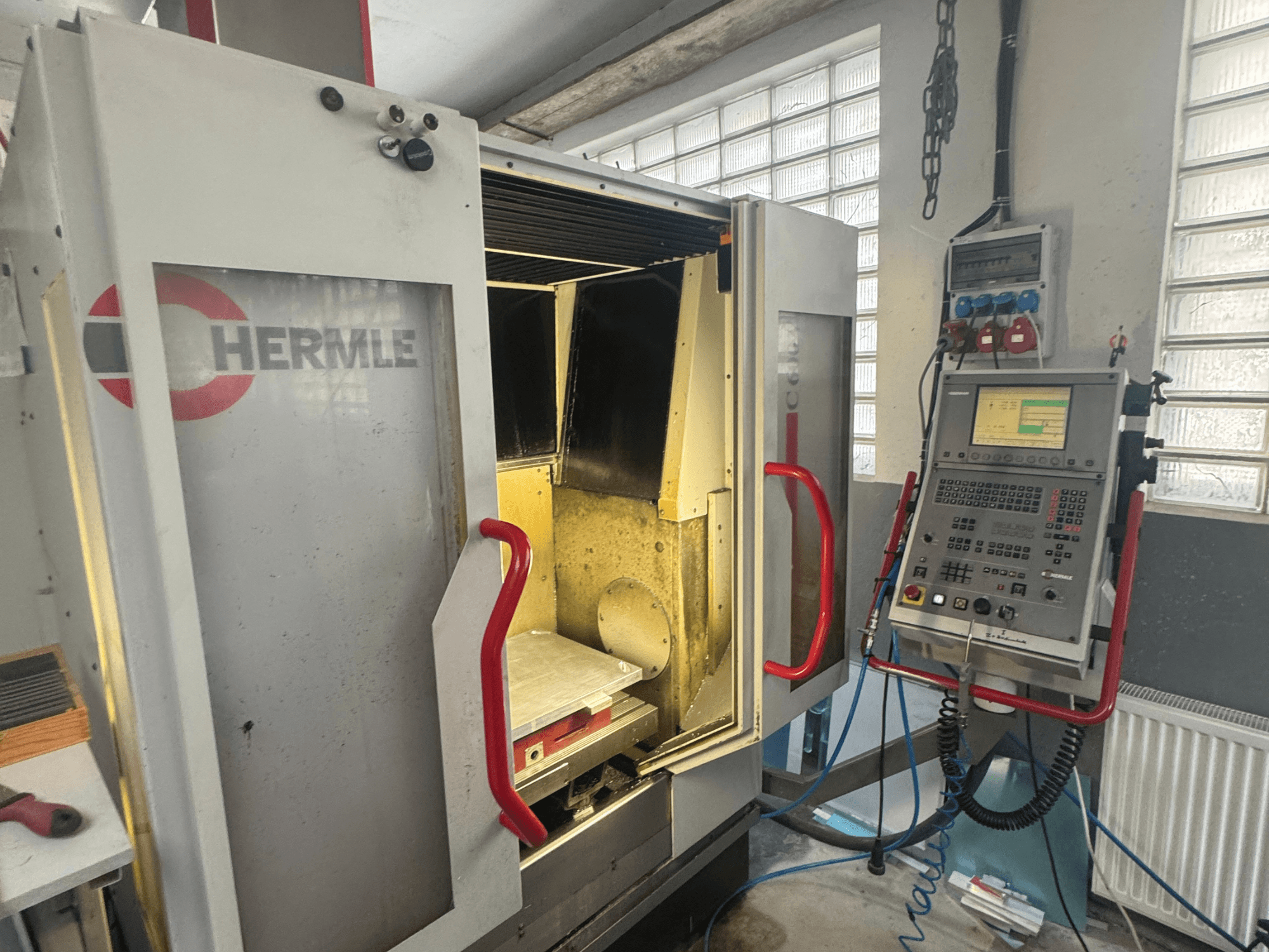 Pionowe centrum obróbcze HERMLE C600V, widok z przodu pokazujący otwarte drzwi, panel sterowania i wewnętrzny obszar roboczy.