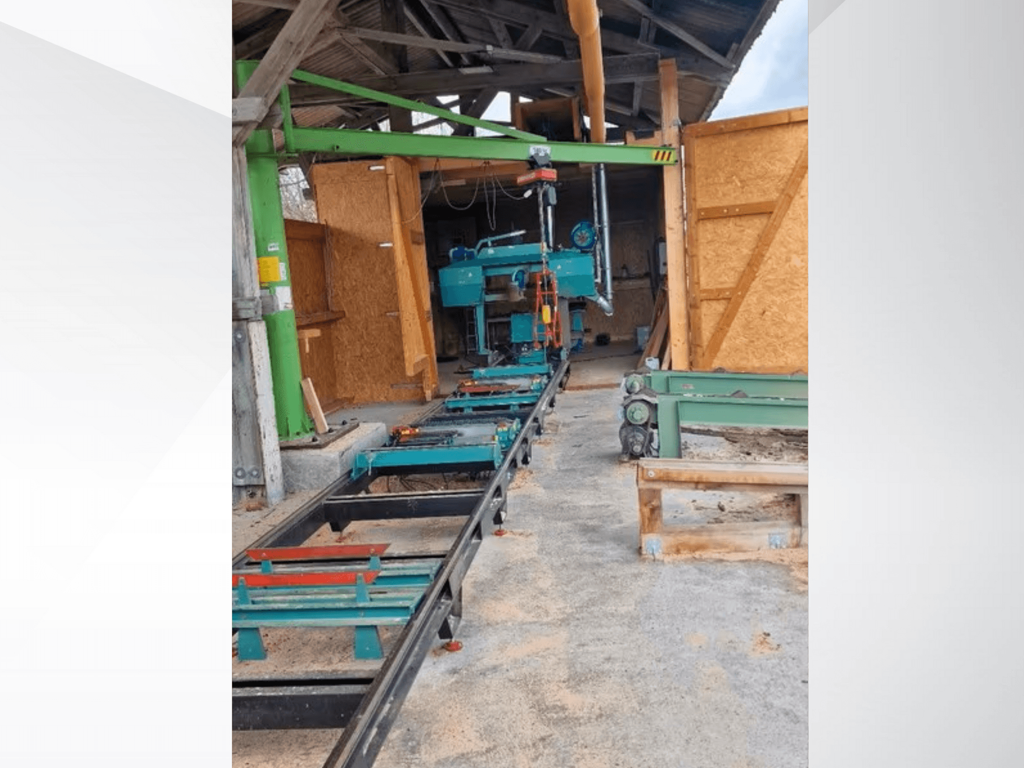 Pozioma przecinarka taśmowa w warsztacie, widziana od przodu. Wyposażenie obejmuje prowadnicę i dodatkowe zielone akcesoria.