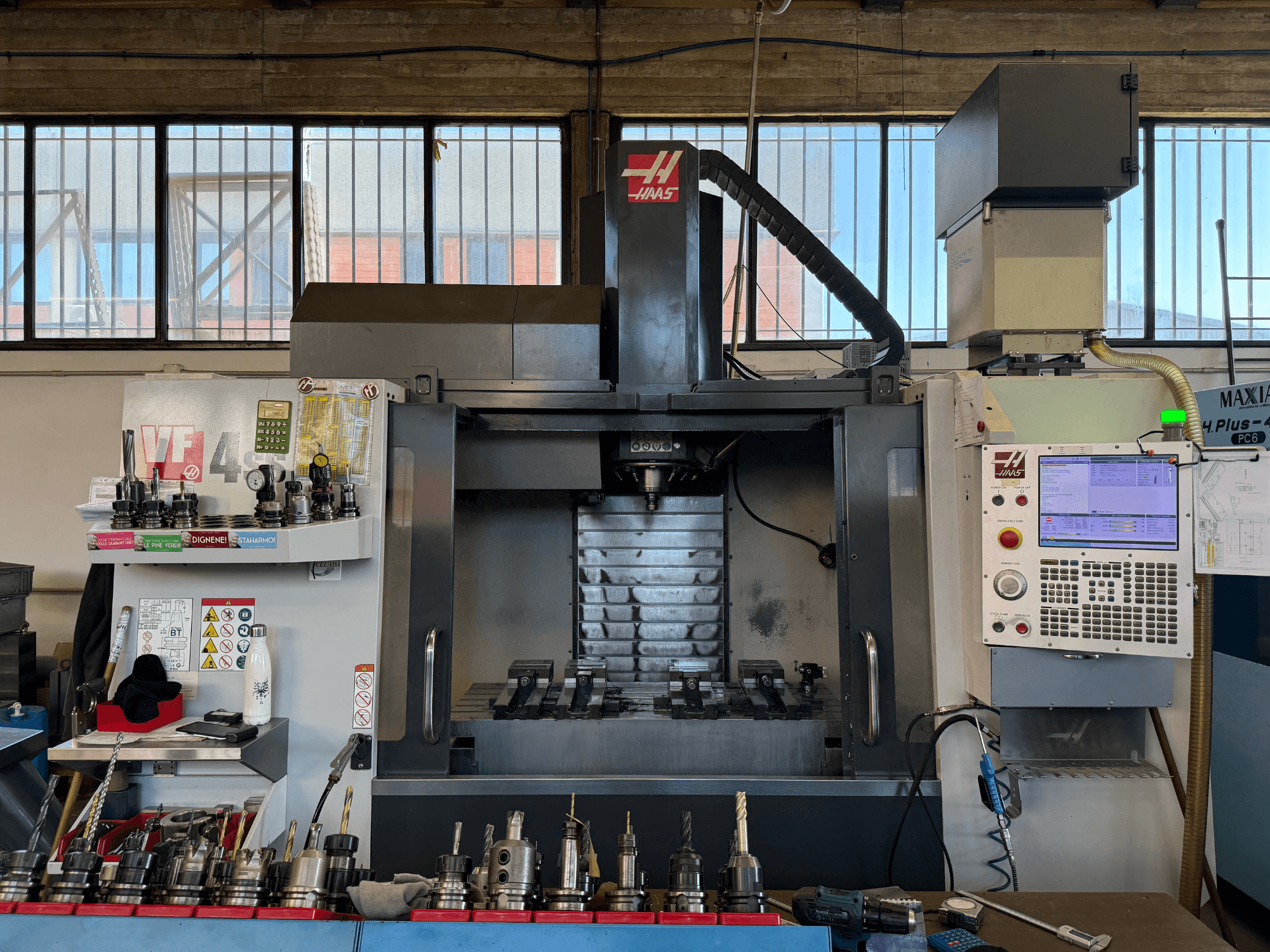 Pionowe centrum obróbcze HAAS VF-4SS, widok z przodu, przedstawiające panel sterowania, uchwyty narzędziowe oraz widoczną część wrzeciona.