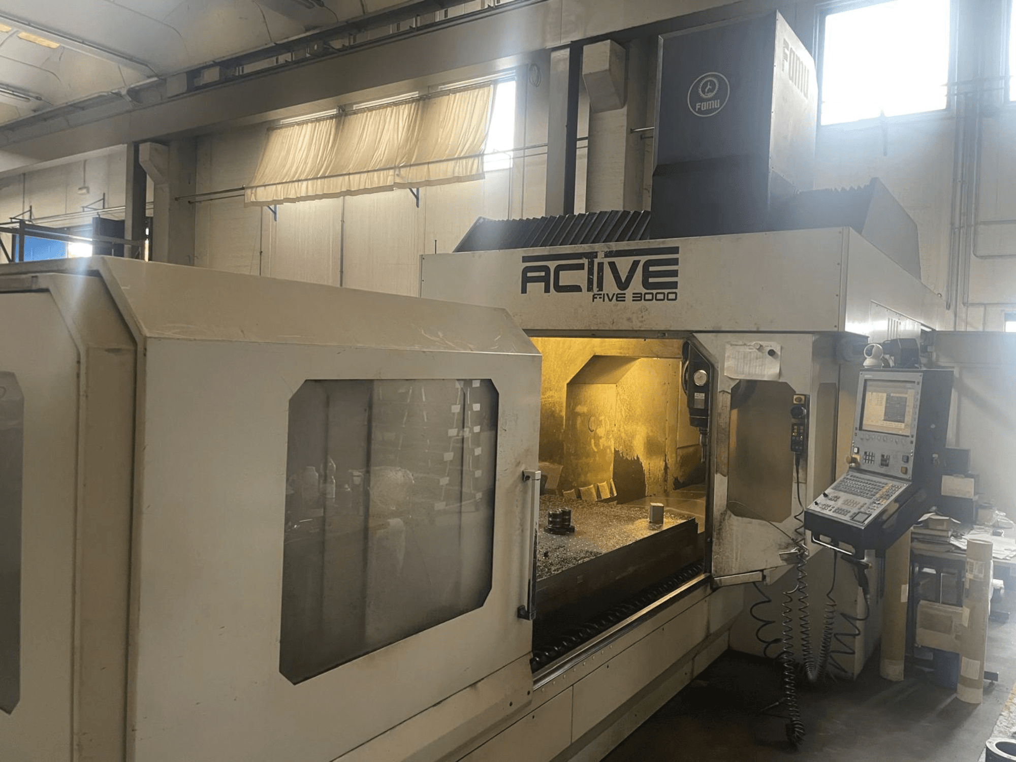 Widok z przodu maszyny CNC ACTIVE Five 3000, pokazujący panel sterowania i obszar roboczy z częściowo obrobionym elementem wewnątrz.