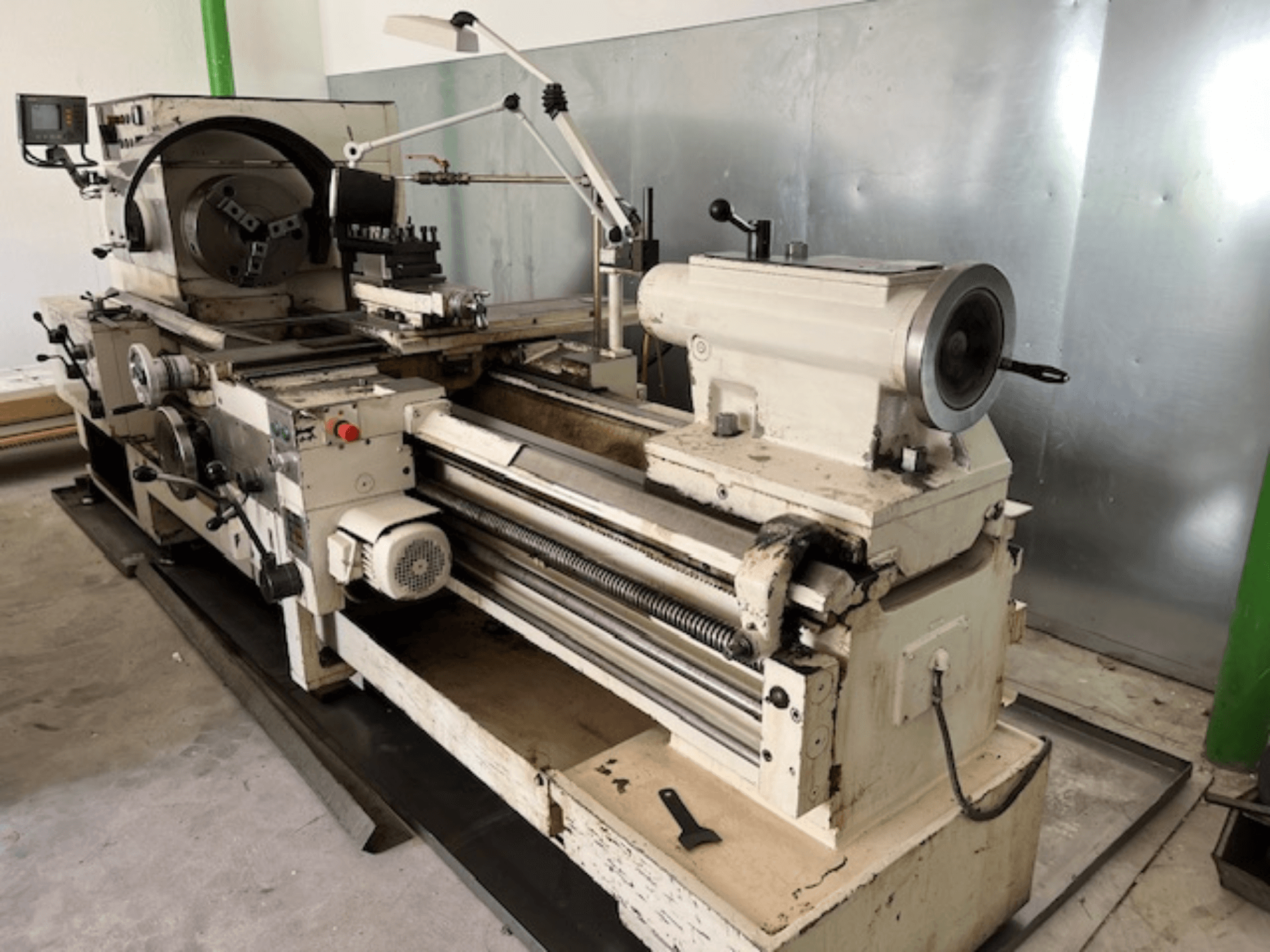 Zabytkowa tokarka do metalu z panelem sterowania i narzędziami, widok z boku, pokazujący elementy operacyjne i metalowe wykończenie.