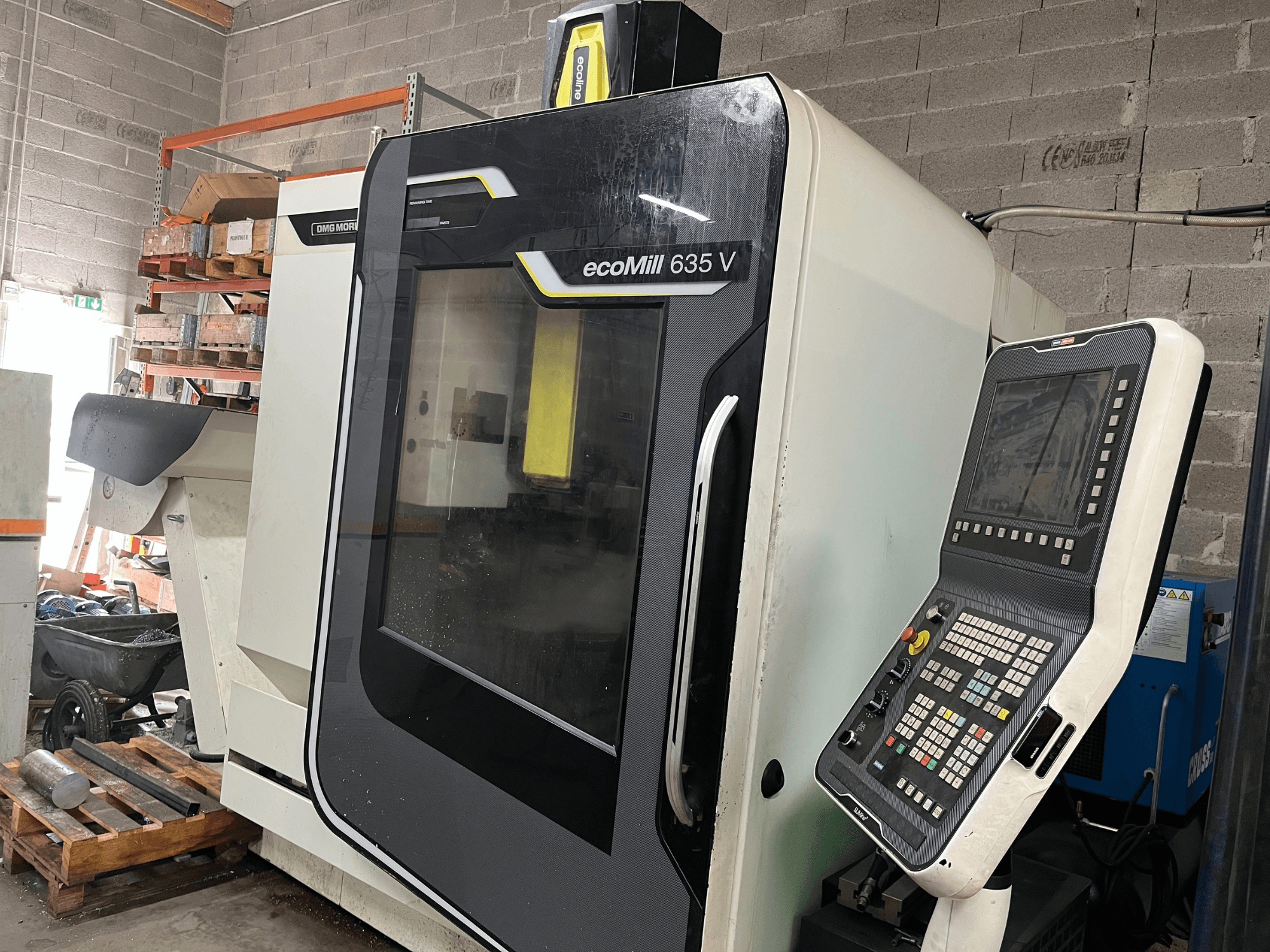 Frezarka CNC EcoMill 635 V, widok z przodu, posiada panel sterowania z przyciskami, umieszczony w przemysłowej przestrzeni roboczej.
