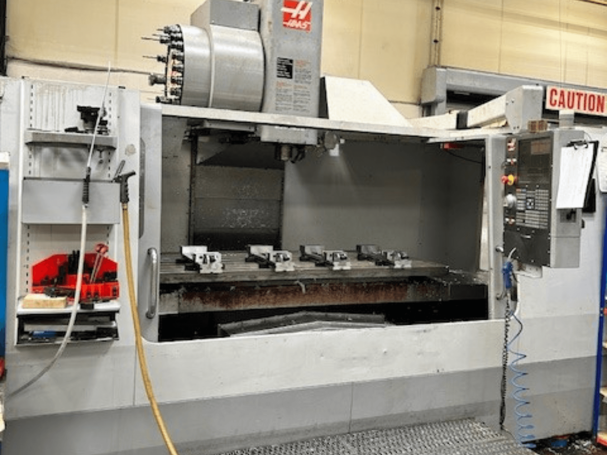 Pionowe centrum obróbcze HAAS VF-9/40HE, widok z przodu, z uchwytem narzędziowym i akcesoriami widocznymi z boku.