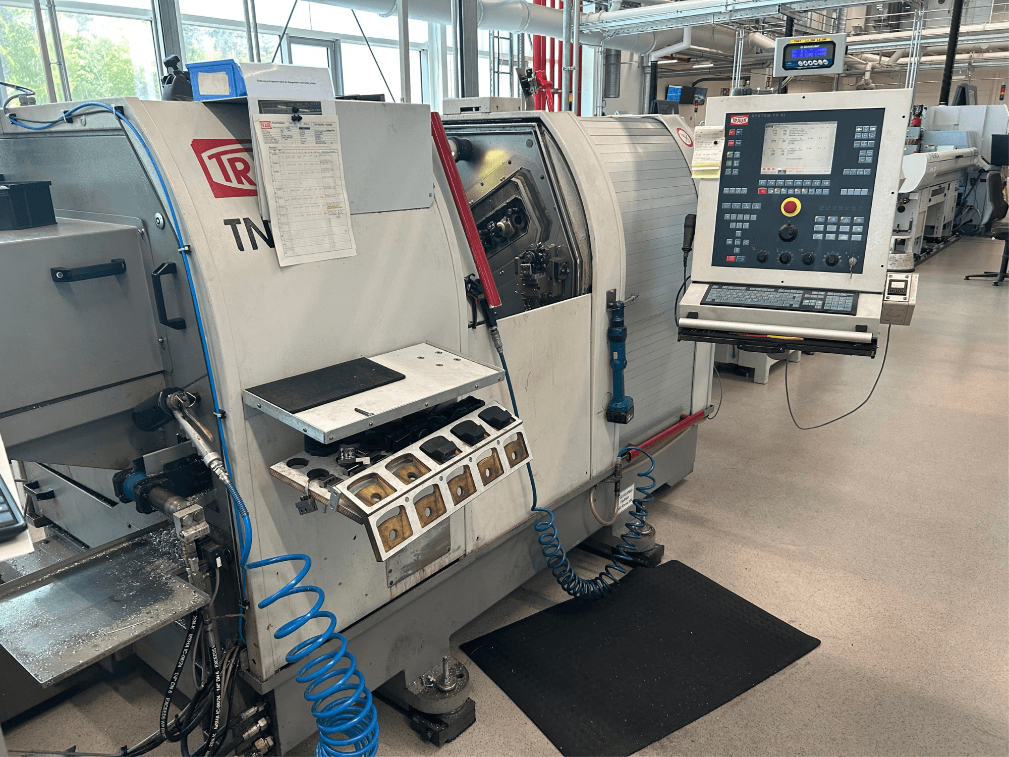 Tokarka pozioma TRAUB TNK 36, widok z przodu, pokazujący panel sterowania, uchwyt narzędziowy i obszar roboczy z wiórami metalowymi.