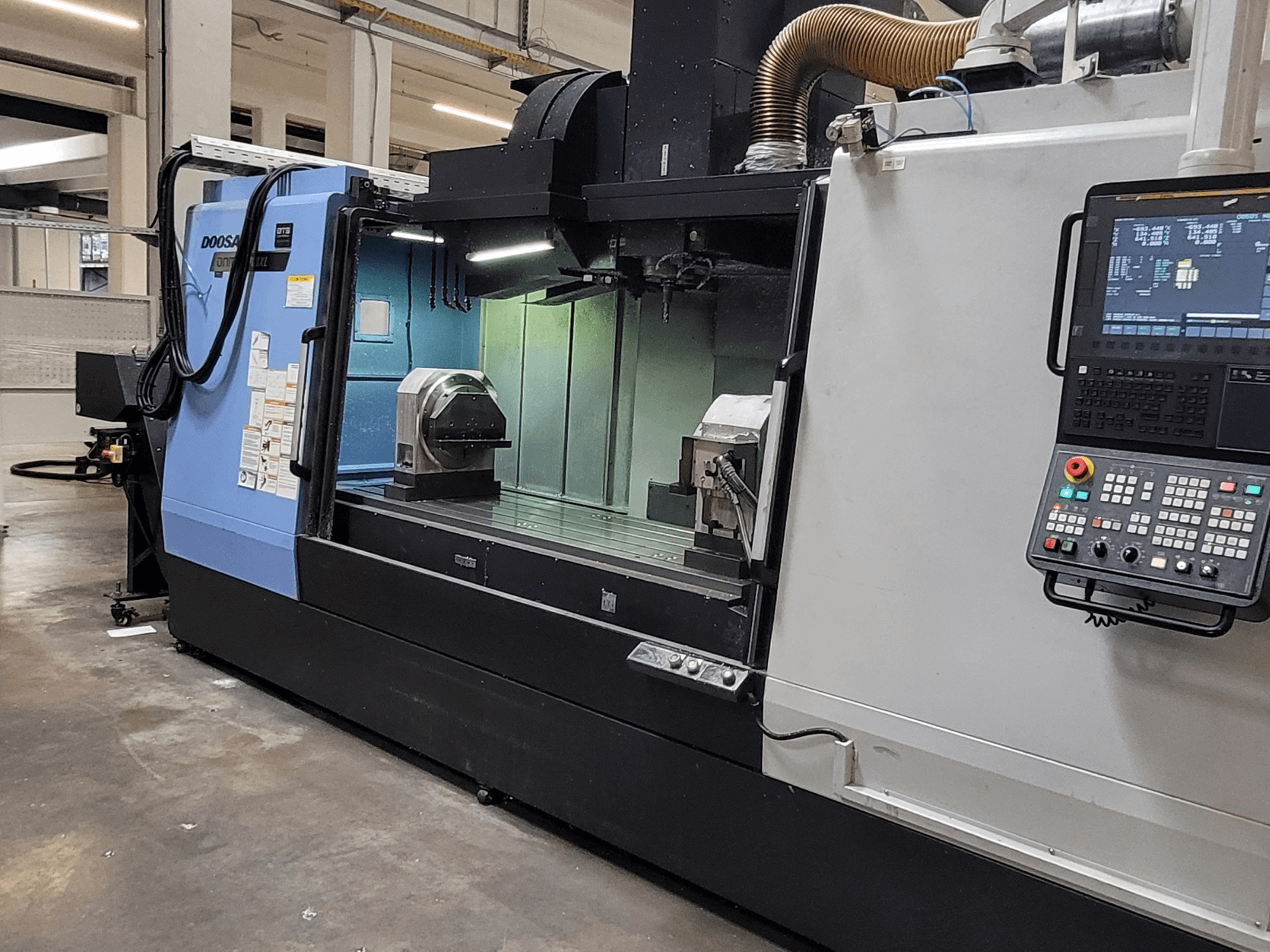 Pionowe centrum obróbcze DOOSAN DNM 6700 XL – widok z przodu przedstawiający panel sterowania, stół roboczy i obszar obróbki.
