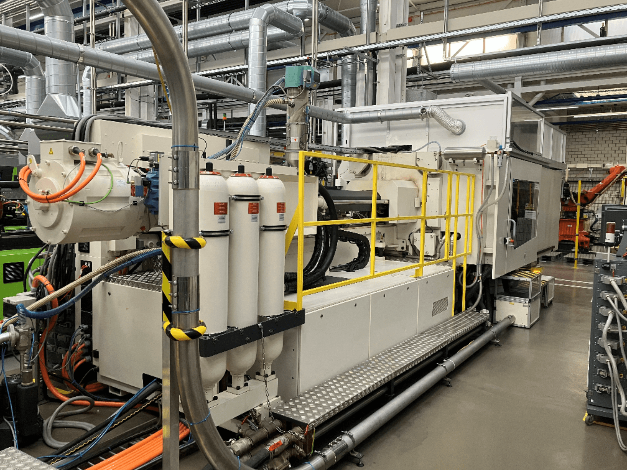 Maszyna przemysłowa z biało-szarą obudową, wieloma wężami i zbiornikami filtrującymi; widok z boku przedstawiający konfigurację operacyjną.