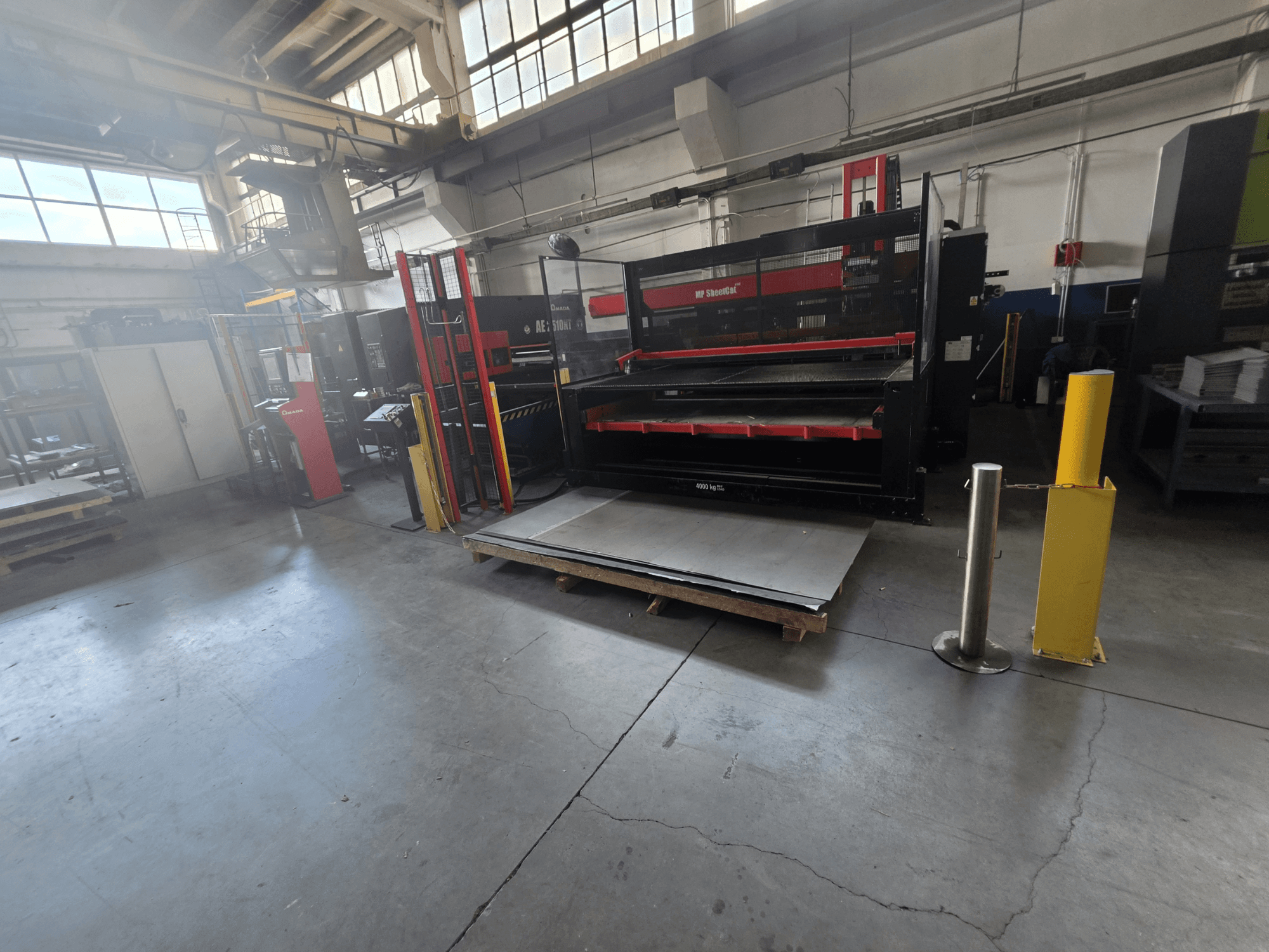 Wykrawarka CNC AMADA AE-2510NT w magazynie, widok z boku, przedstawiający konfigurację maszyny i blachy.