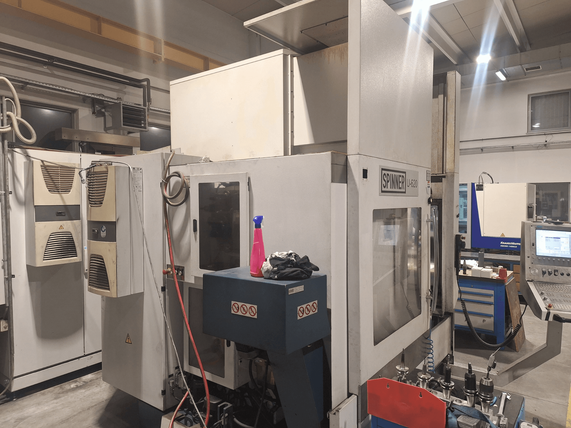 Maszyna CNC Spinner U-620 pokazana z przodu w warsztacie, z panelem sterowania i różnymi narzędziami na stole warsztatowym w pobliżu.
