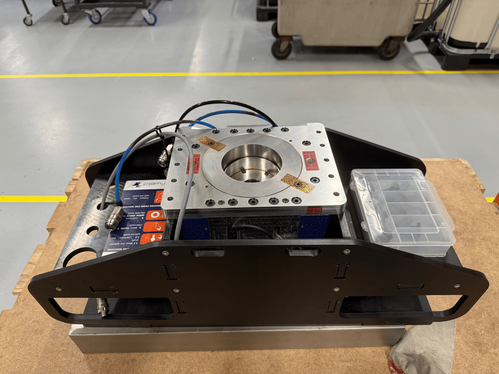 Obrabiany maszynowo metalowy element z niebieskimi kablami, obudową na akcesoria i płaską podstawą, pokazany z góry, idealny do zastosowań mechanicznych.