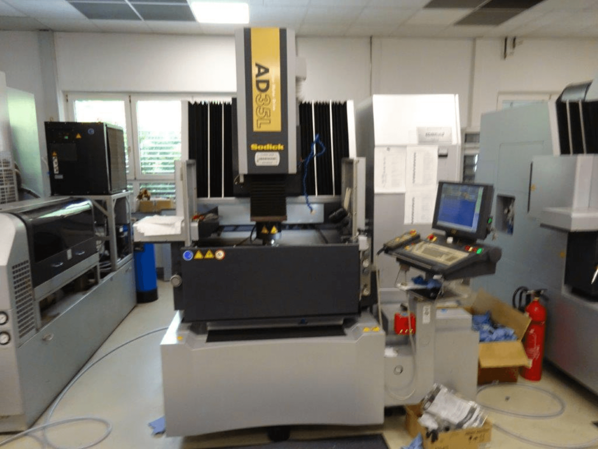 Maszyna CNC Sodick AD35L w widoku z przodu, z panelem sterowania, jednostką chłodzącą i wskaźnikami bezpieczeństwa.