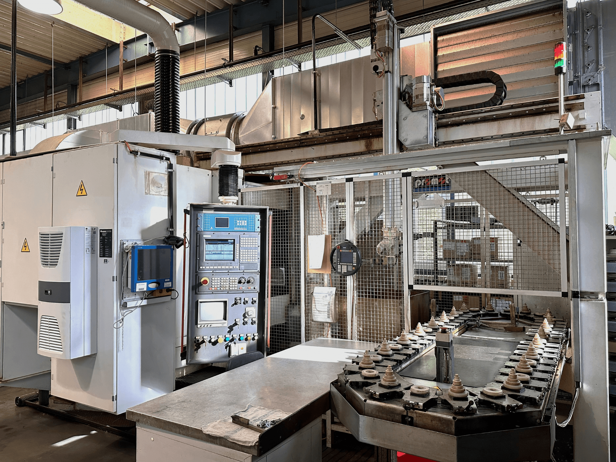 Maszyna przemysłowa z panelem sterowania, jednostką chłodzącą i przenośnikiem. Widok z przodu z jasnymi światłami i oznakowaniem bezpieczeństwa.