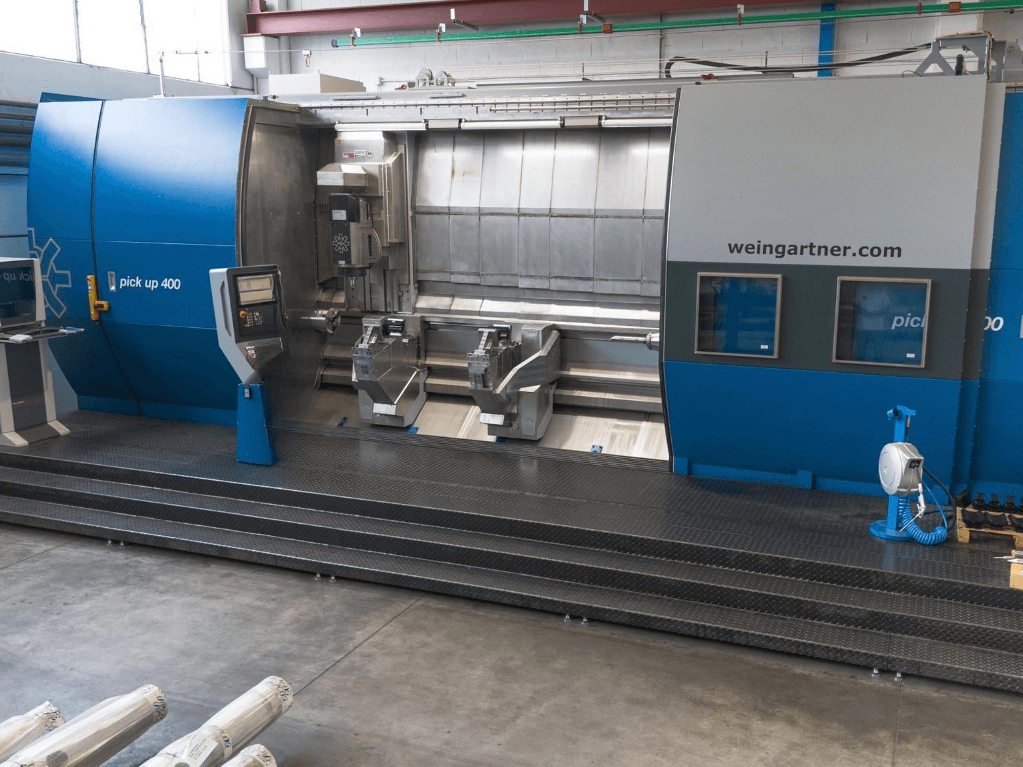 Centrum obróbcze Weingartner Pick Up 400 typu „mill-turn”, widok z przodu. Wyposażone w dwa stanowiska robocze i panel sterowania, w środowisku przemysłowym.