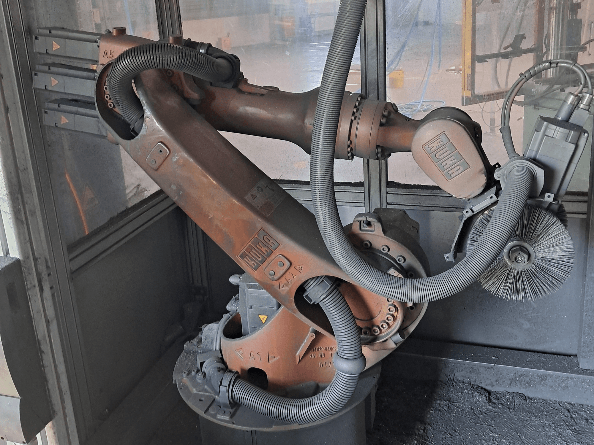 Ramię robota KUKA KR 16-2 widziane z boku, z widocznymi kablami, szczotkami i przegubami mechanicznymi, umieszczone w środowisku roboczym.