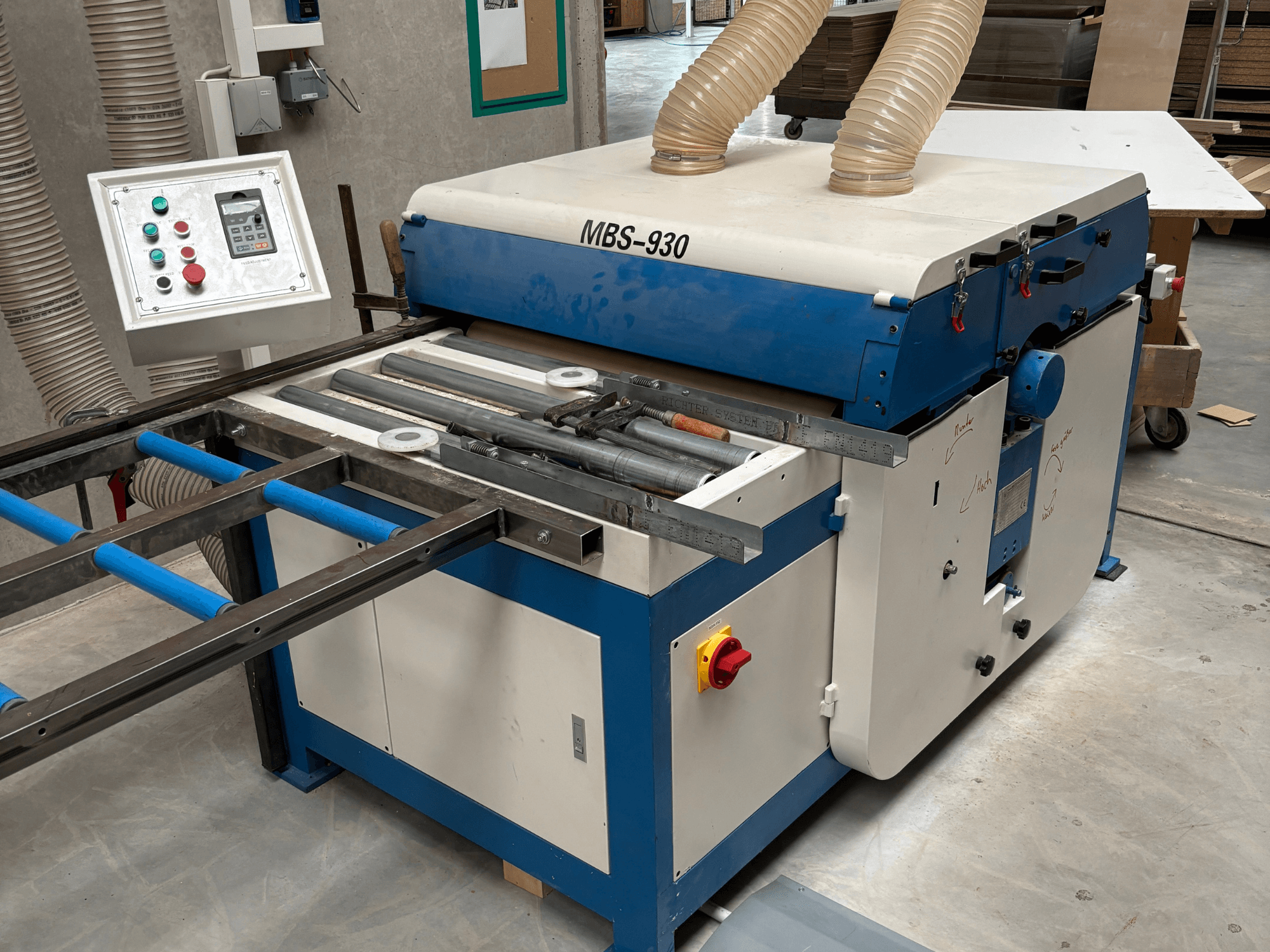 Maszyna do obróbki drewna MBS-930 z panelem sterowania i rolkami, widziana z boku, wyposażona w węże odpylające.