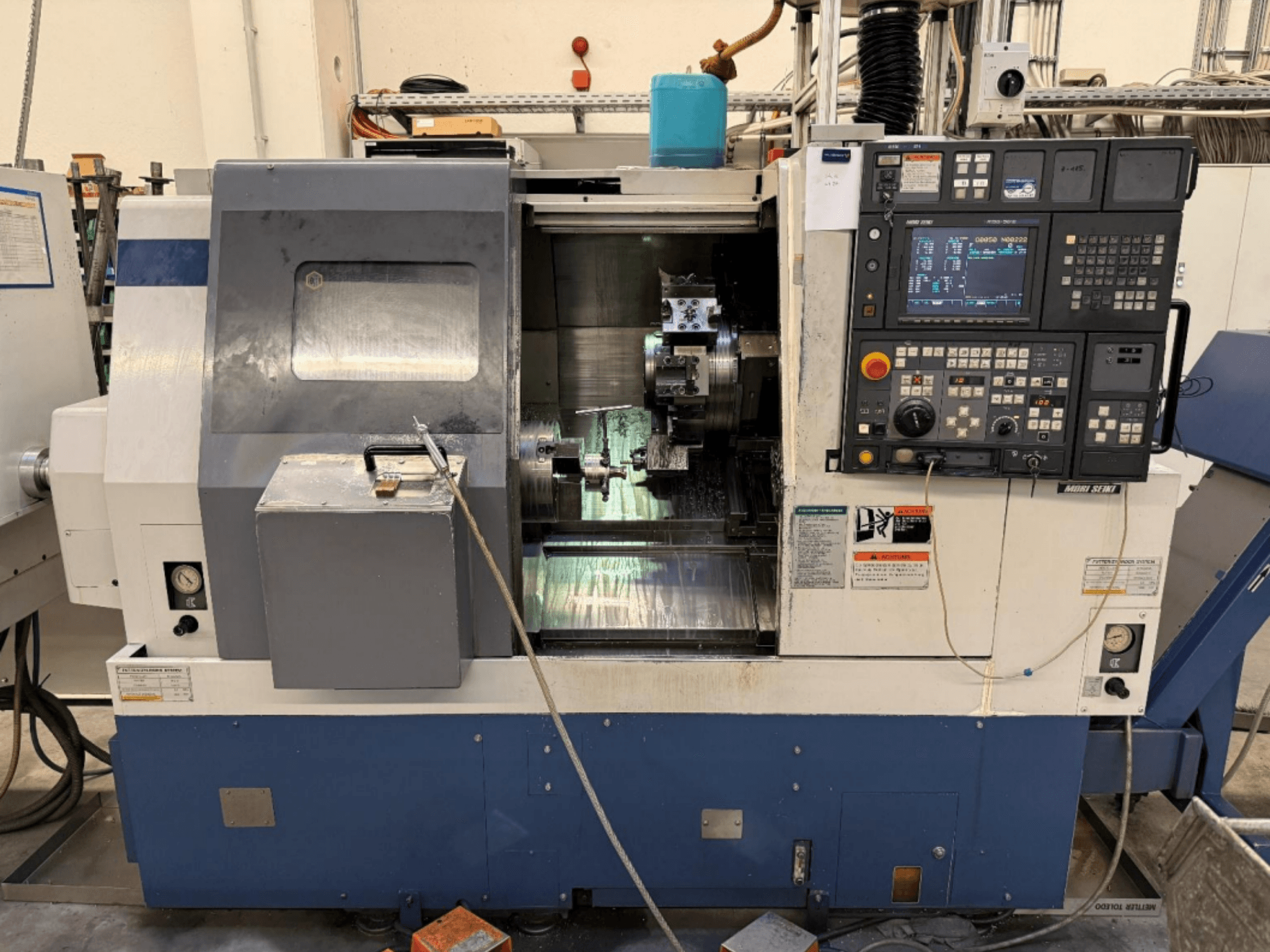 Centrum tokarsko-frezarskie MORI SEIKI SL-250ASMC – widok z przodu przedstawiający panel sterowania i uchwyt obrabianego elementu podczas pracy.