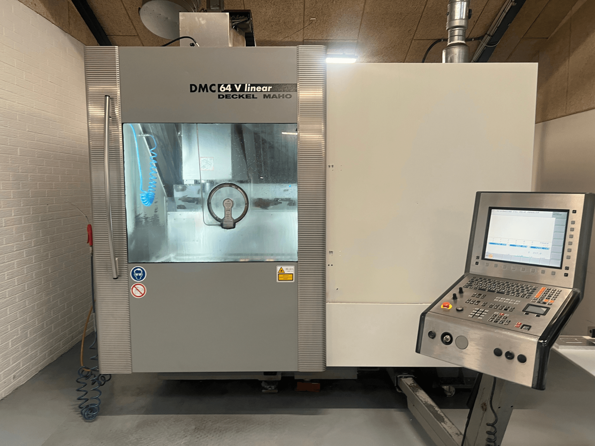 DMC 64 V Linear firmy Deckel Maho, widok z przodu centrum obróbczego CNC z widocznym panelem sterowania i dyszą chłodziwa.
