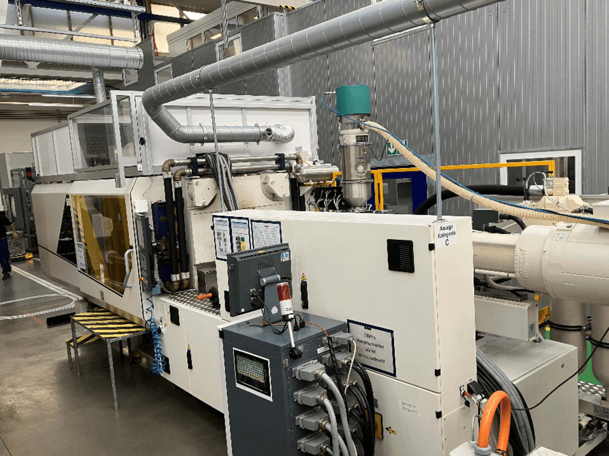 Wtryskarka, widok z przodu, z etykietą marki, panelem sterowania i widocznymi wężami w warunkach fabrycznych.