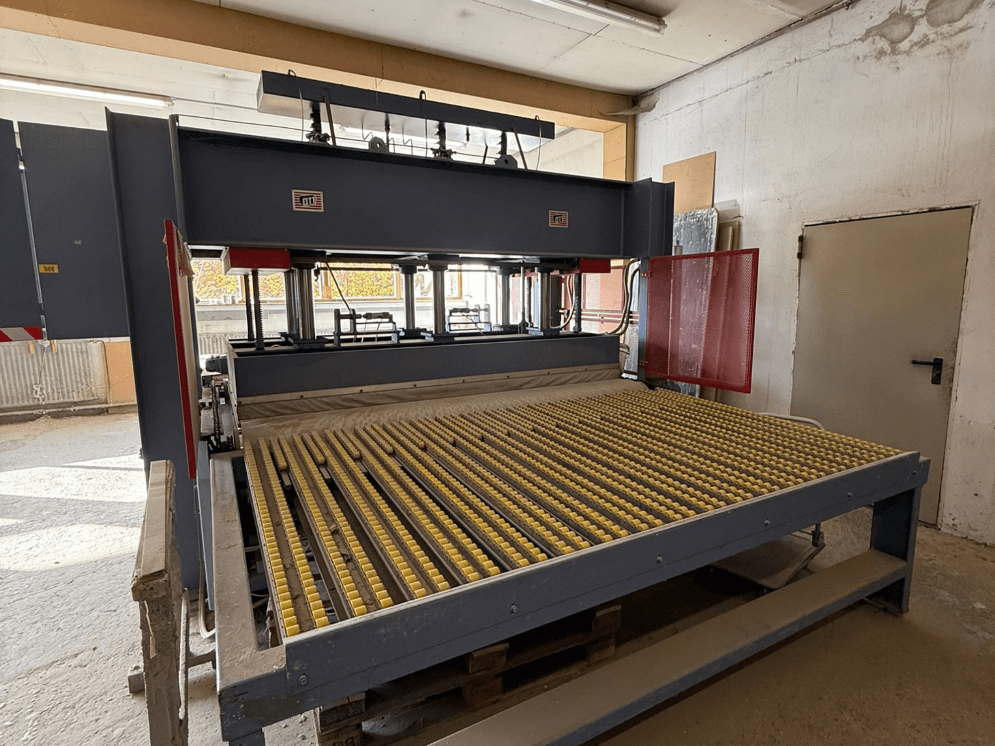 Maszyna przemysłowa z żółtymi rolkami, widok z przodu, widoczne logo marki, używana do obróbki materiałów w warunkach warsztatowych.