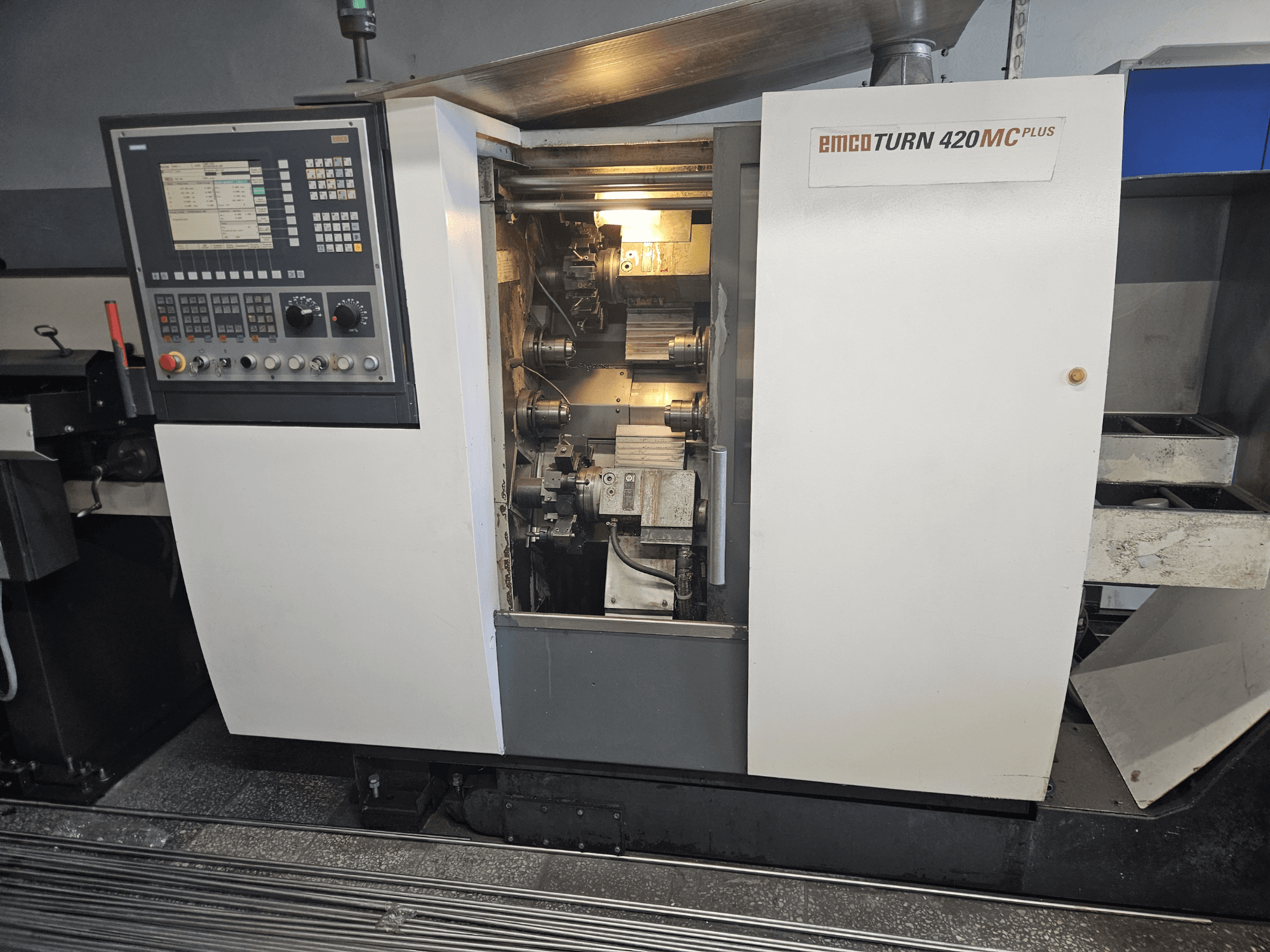 Maszyna wielowrzecionowa EMCO TURN 420 MC Plus, widok z przodu przedstawiający panel sterowania i elementy wewnętrzne.