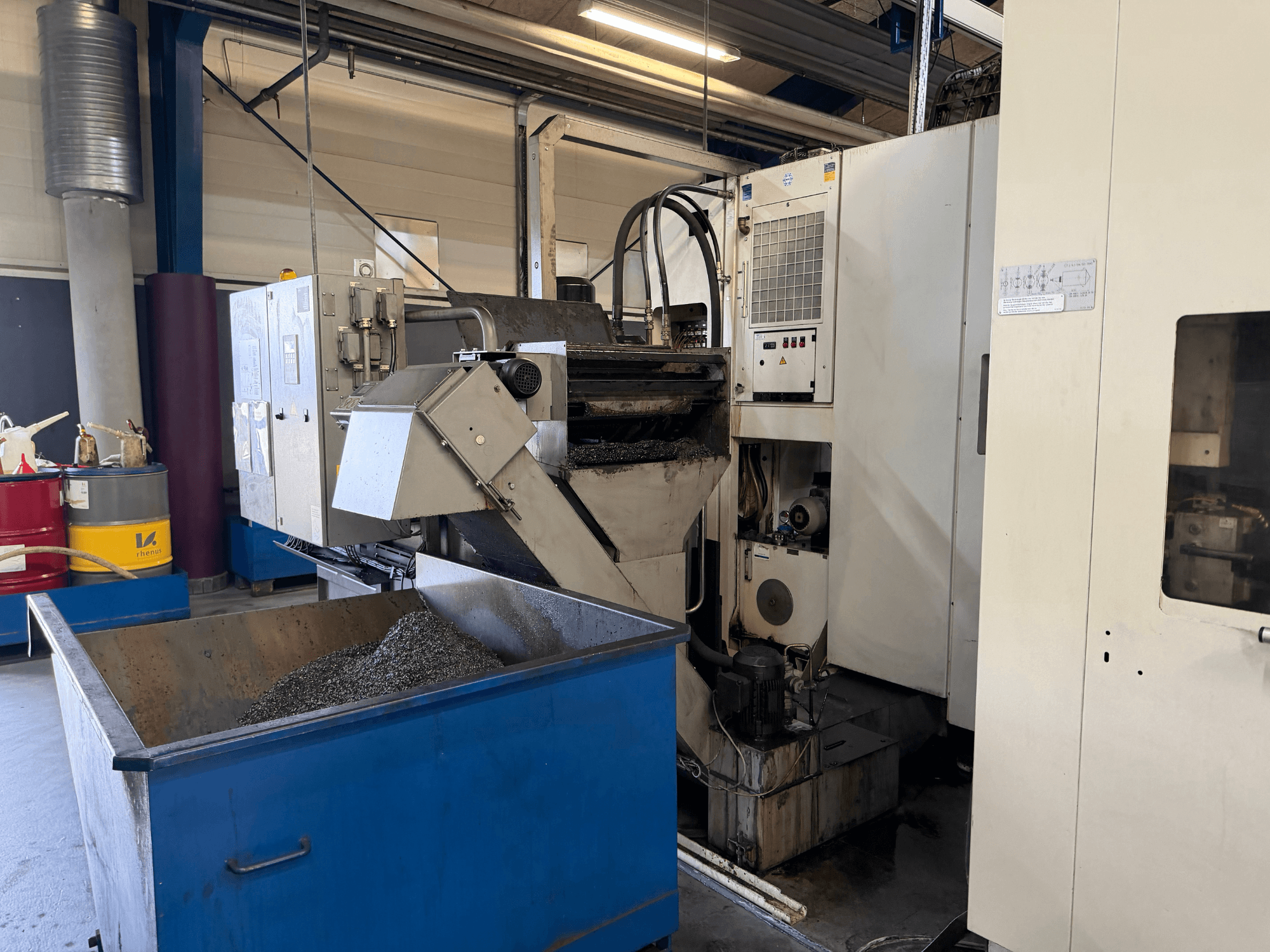 Widok z przodu poziomego centrum obróbczego HELLER MCH 250 z widocznym pojemnikiem na chłodziwo i panelem sterowania.