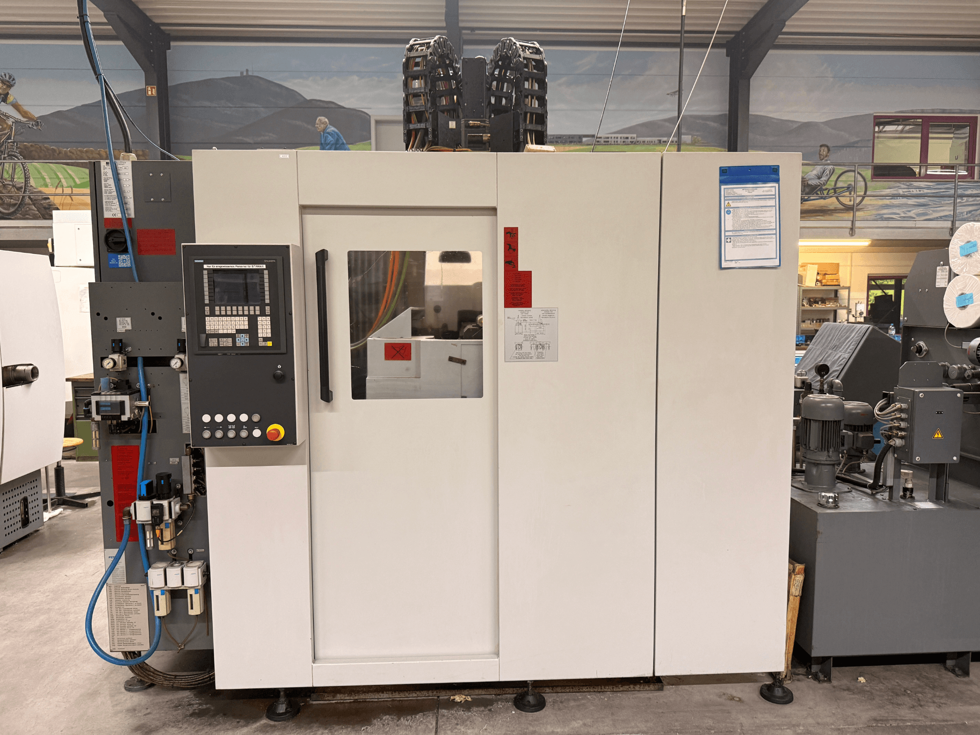 Białe centrum obróbcze CNC z panelem sterowania, widok z przodu, z przyciskami i wyświetlaczem cyfrowym, w warunkach warsztatowych.