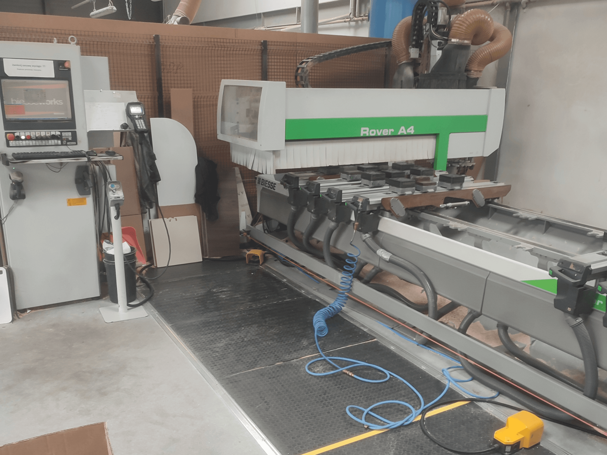 Centrum obróbki drewna BIESSE Rover A4 CNC widziane z boku, z widocznym panelem sterowania, uchwytami próżniowymi oraz systemem odpylania.