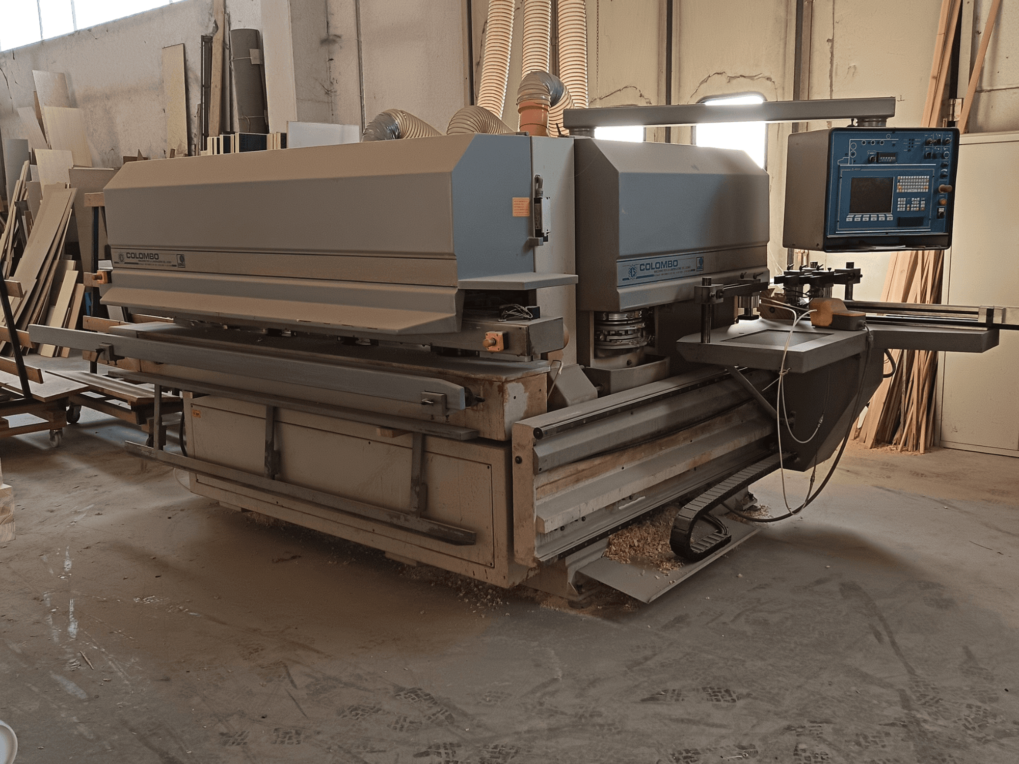 Maszyna do obróbki drewna Colombo, widok z boku, pokazujący panel sterowania, ostrza tnące i gromadzenie się pyłu w warsztacie.