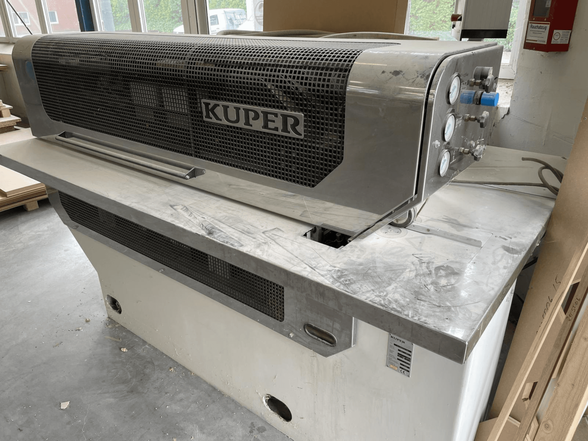 Gilotyna do forniru KUPER FLI, widok z przodu, z korpusem ze stali nierdzewnej, wskaźnikami i czystym obszarem cięcia na stole warsztatowym.