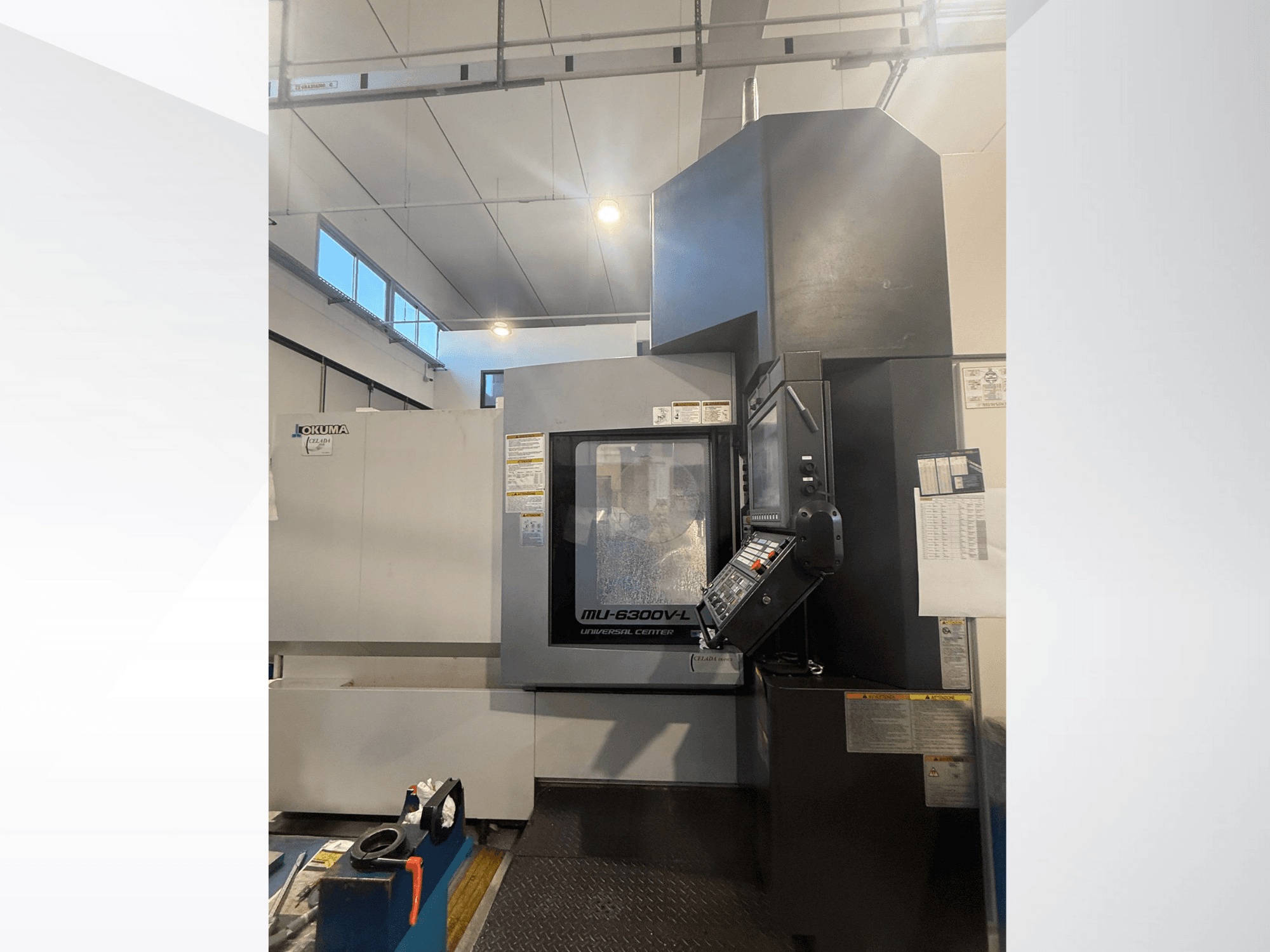 Maszyna CNC Okuma MU-6300V-L widziana od przodu, z panelem sterowania i etykietami bezpieczeństwa.