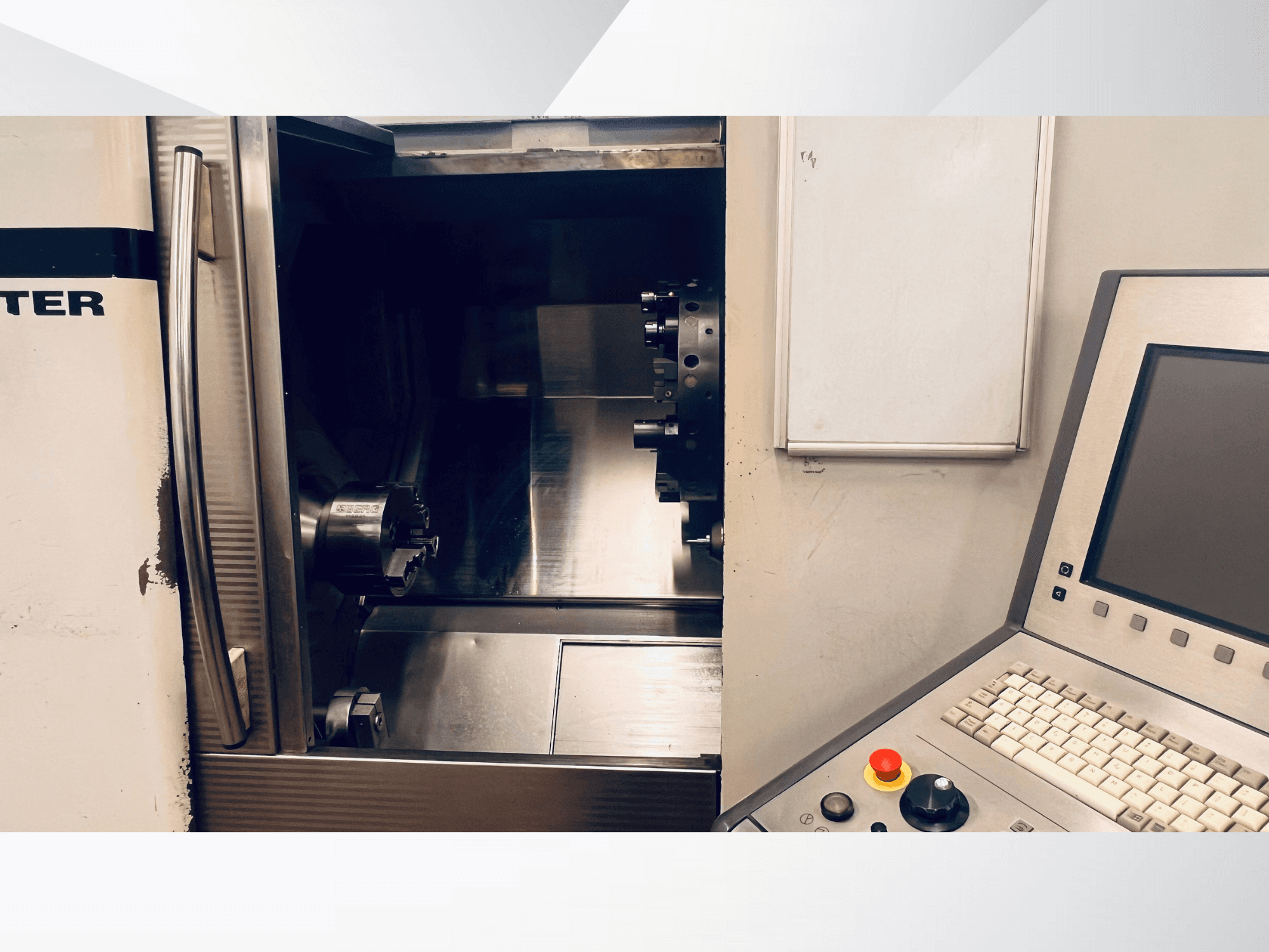 Widok maszyny CNC z przodu przedstawiający otwartą komorę i panel sterowania z klawiaturą i przyciskiem zatrzymania awaryjnego.