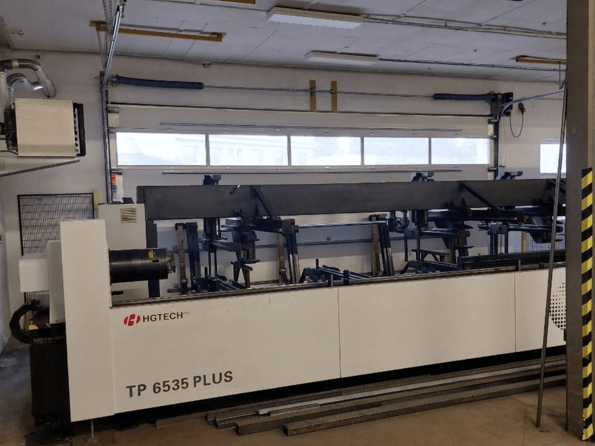 HGTECH TP 6535 PLUS, widok z przodu dużej maszyny przemysłowej z wieloma ramionami do precyzyjnej produkcji, ustawionej w warsztacie.