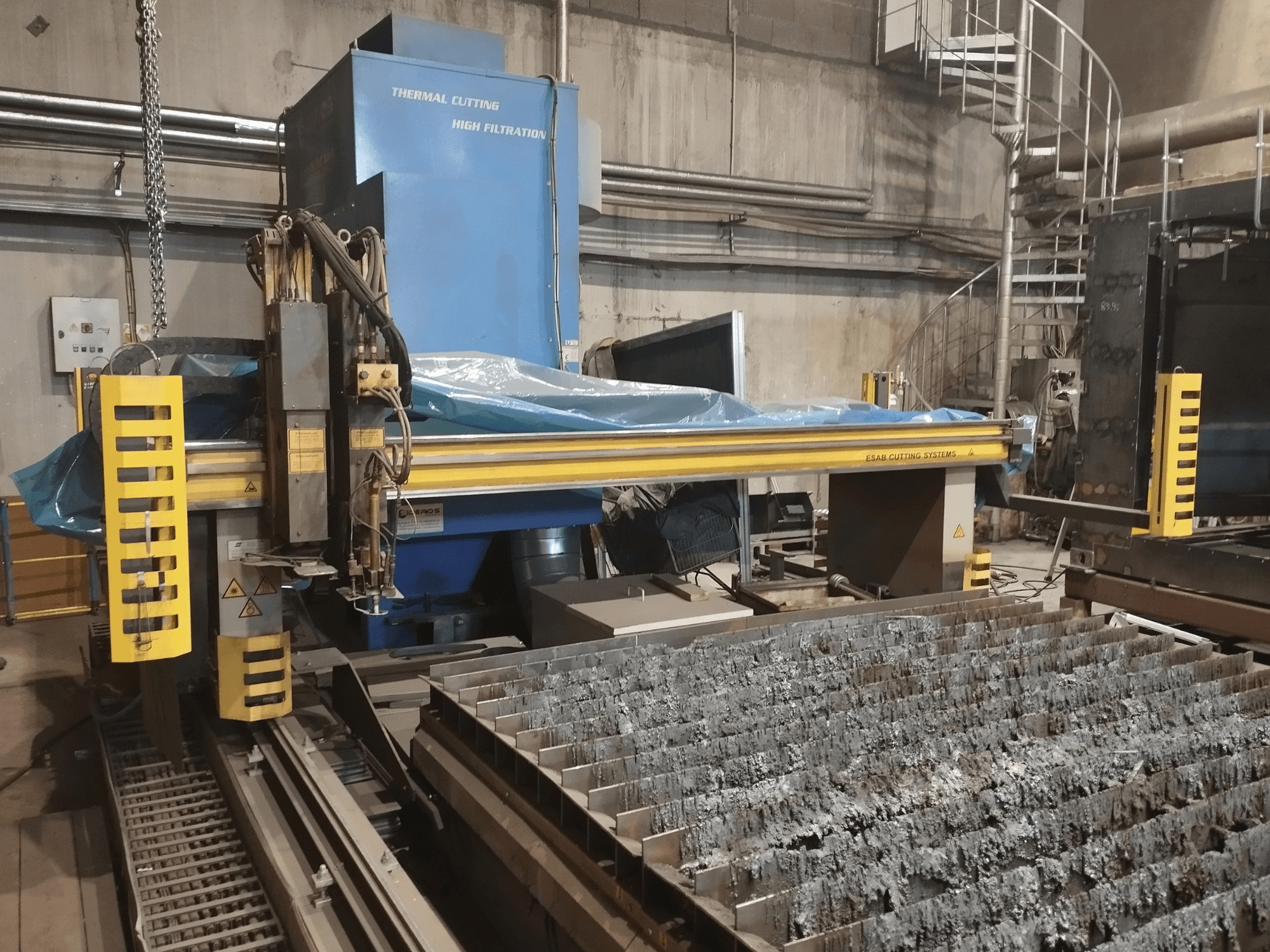 Przecinarka plazmowa ESAB Combirex DX3500 Oxy, widok z przodu, z żółtymi zabezpieczeniami i stołem do cięcia metalu.