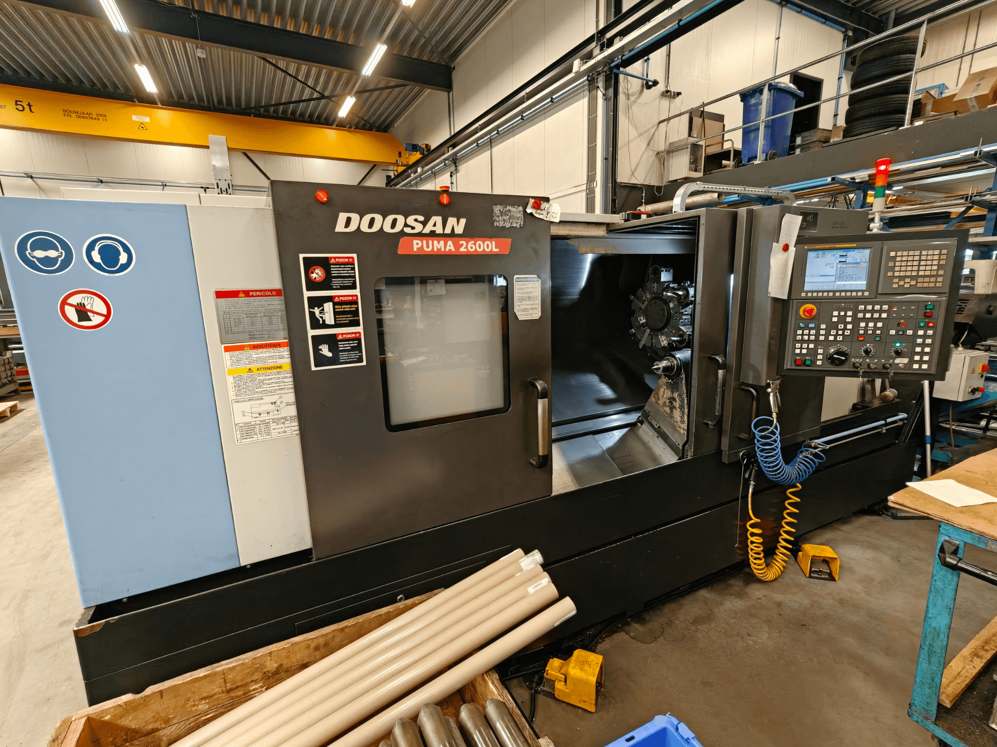Tokarka pozioma DOOSAN Puma 2600L w warsztacie, widok z boku pokazujący panel sterowania i obszar wrzeciona.