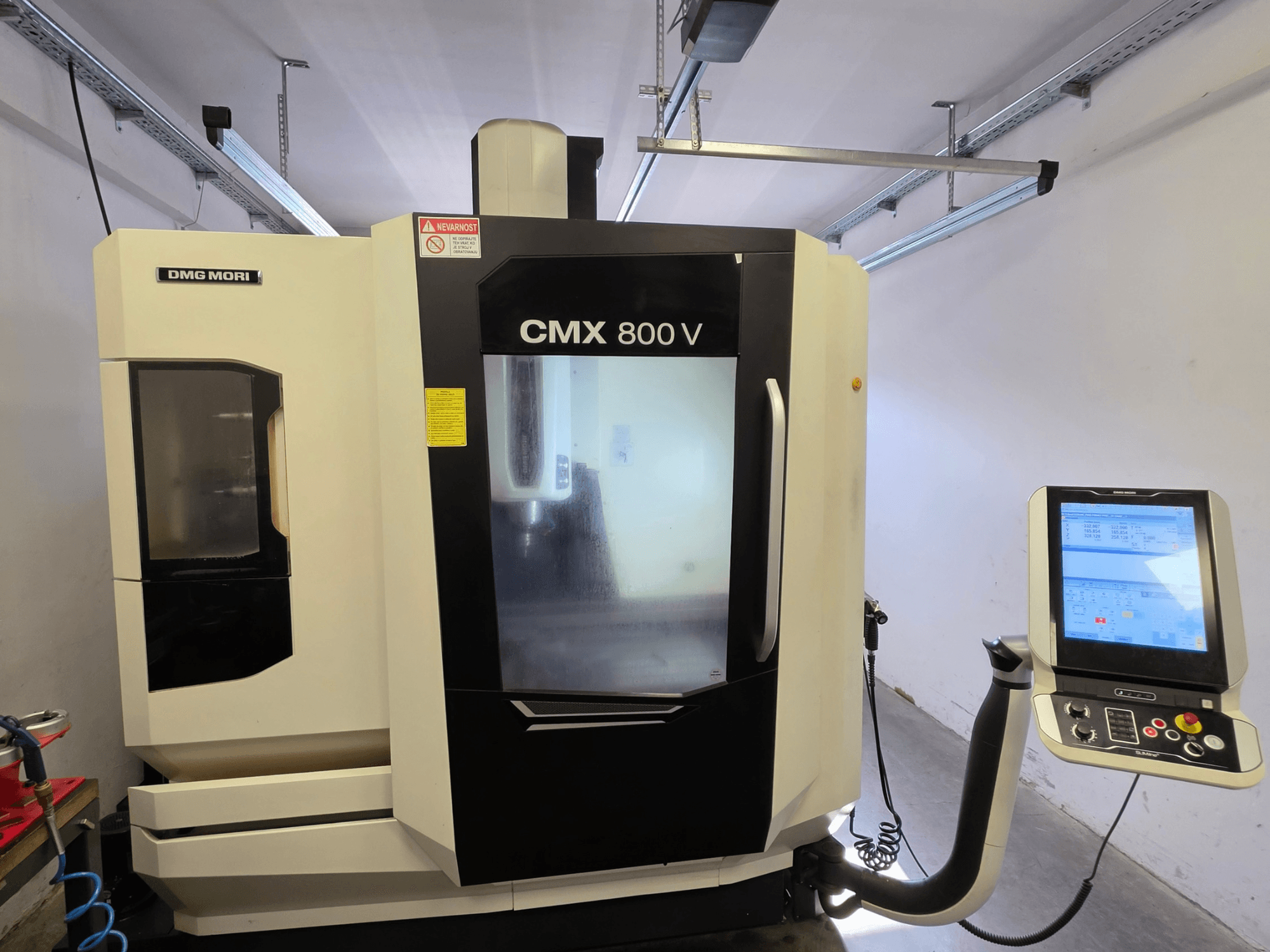 Pionowe centrum obróbcze DMG MORI CMX 800V, widok z przodu, wyposażone w panel sterowania z ekranem dotykowym oraz wyraźne oznakowanie bezpieczeństwa.
