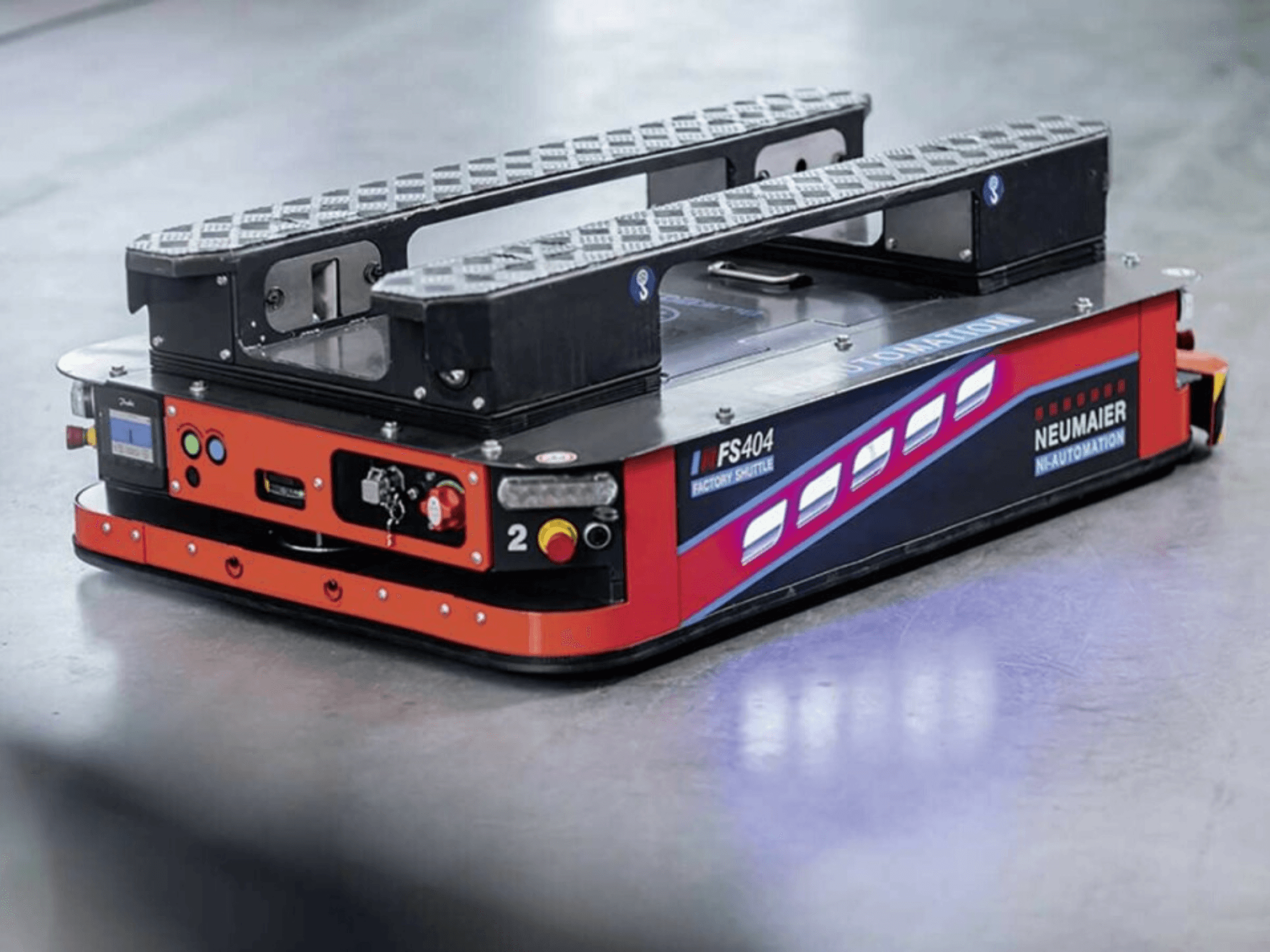 NEUMAIER AGV Factory Shuttle FS404, niskoprofilowy system obsługi palet, widok z boku pokazujący koła, elementy sterujące i funkcje bezpieczeństwa.