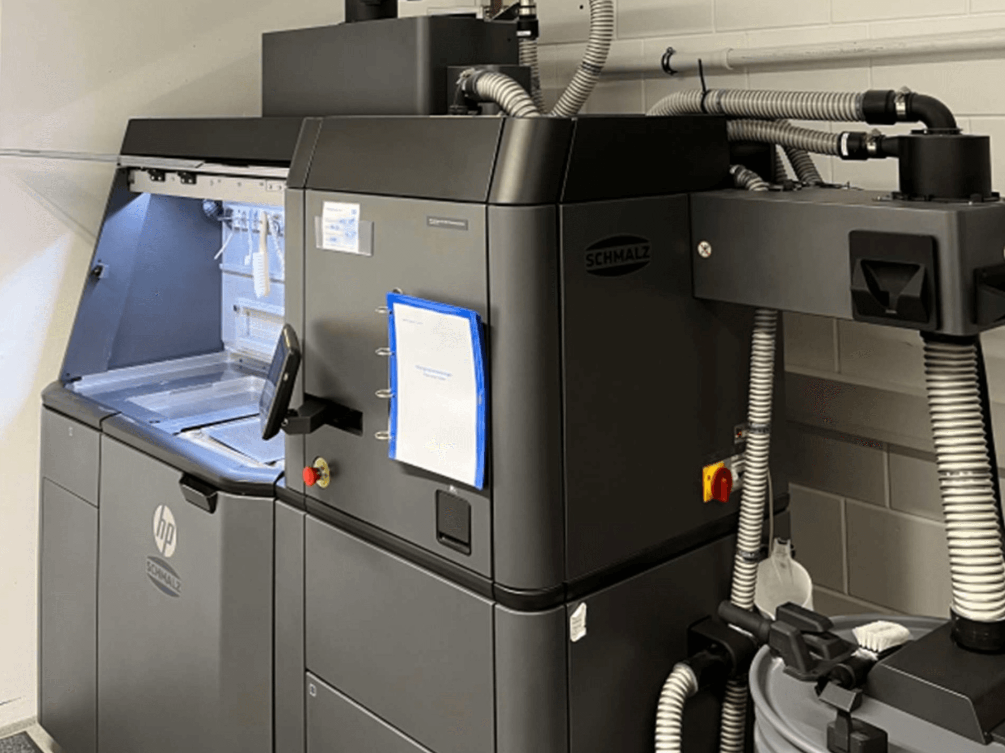 Drukarka 3D HP Jet Fusion 3D 4200 do druku z tworzyw sztucznych, widok z boku, przedstawiający panel sterowania i elementy wewnętrzne.