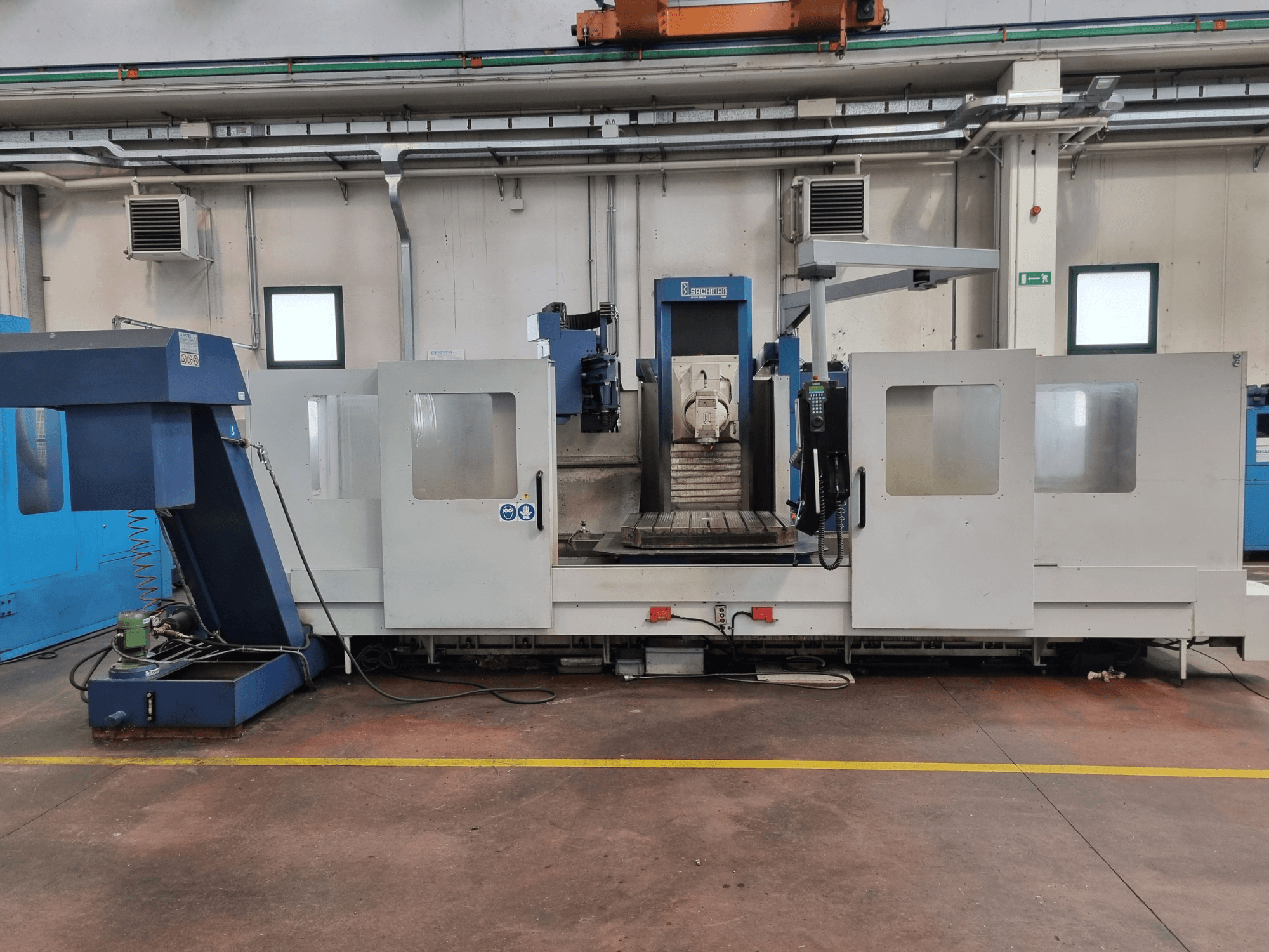 Frezarka CNC firmy "Brembana", widok z boku pokazujący panel sterowania i obszar roboczy ze stołem roboczym wewnątrz.