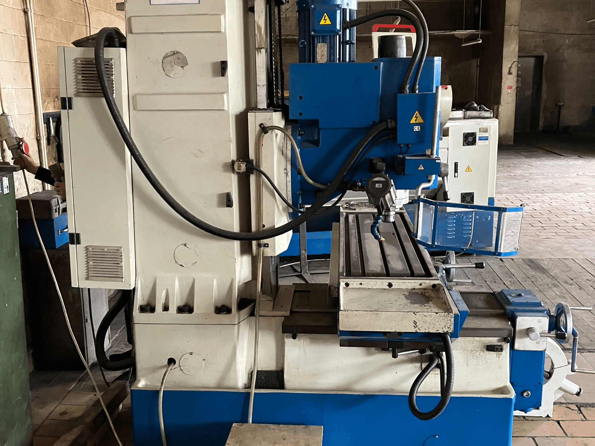 Pionowe centrum obróbcze KNUTH KB 1400, widok z przodu przedstawiający panel sterowania, narzędzie skrawające oraz stół roboczy z prowadnicami liniowymi.