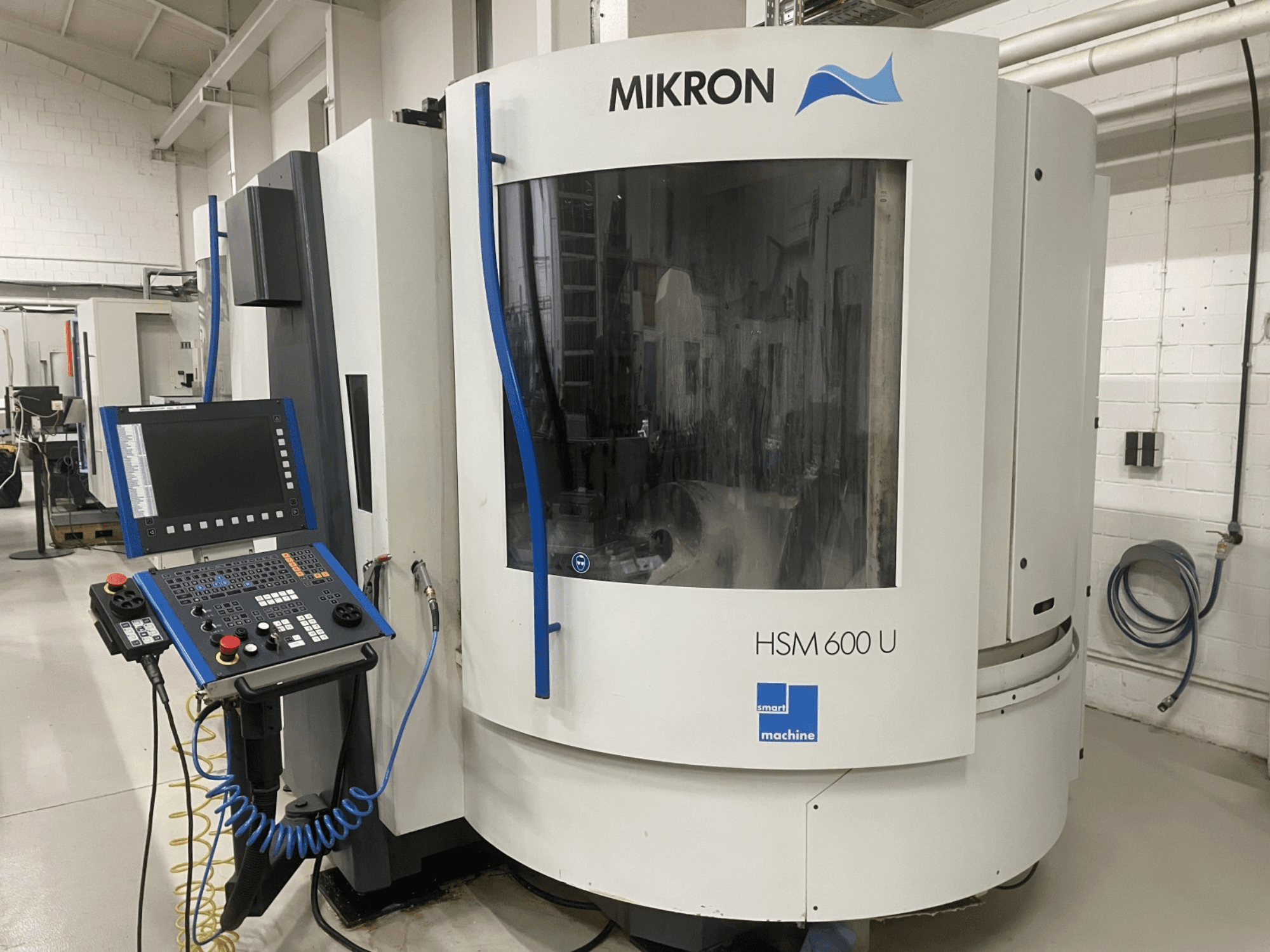 Pionowe centrum obróbcze MIKRON HSM600U pokazane od przodu, z panelem sterowania i dużym oknem podglądu.