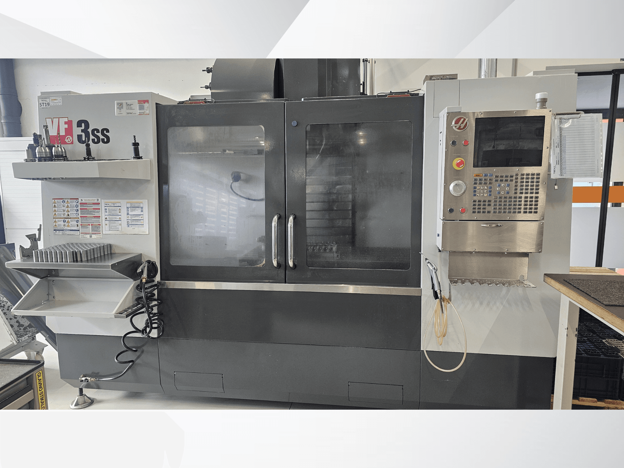 Pionowe centrum obróbcze HAAS VF-3SS, widok z przodu, z panelem sterowania, stojakiem na narzędzia i dużymi szklanymi drzwiami.
