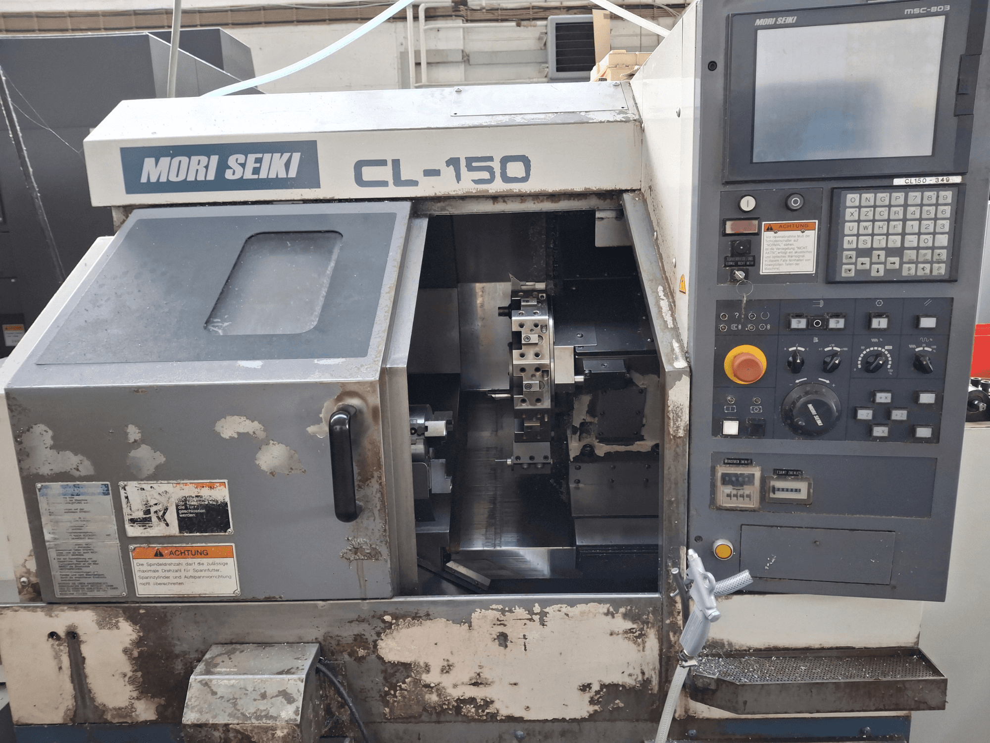 Tokarka pozioma MORI SEIKI CL-150, widok z przodu. Zawiera panel sterowania, narzędzia tnące i wyświetlacze operacyjne.
