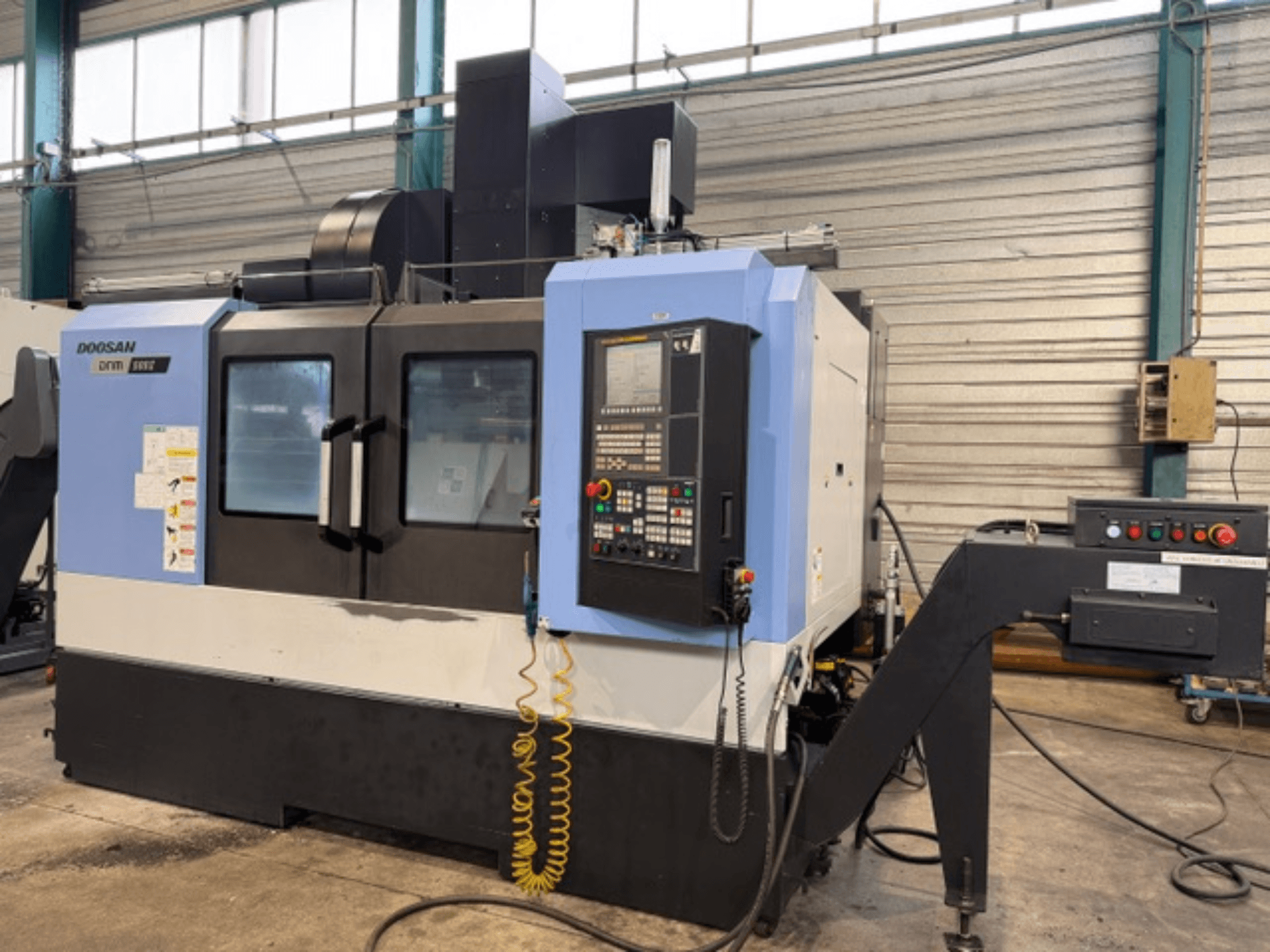 Frezarka CNC Doosan DNM 500II w widoku z przodu, z panelem sterowania i uchwytem narzędziowym, w warunkach fabrycznych.