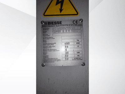 Tabliczka ze specyfikacją techniczną centrum obróbczego NC firmy Biesse, zawierająca informacje o napięciu, wadze i mocy, widok z boku.