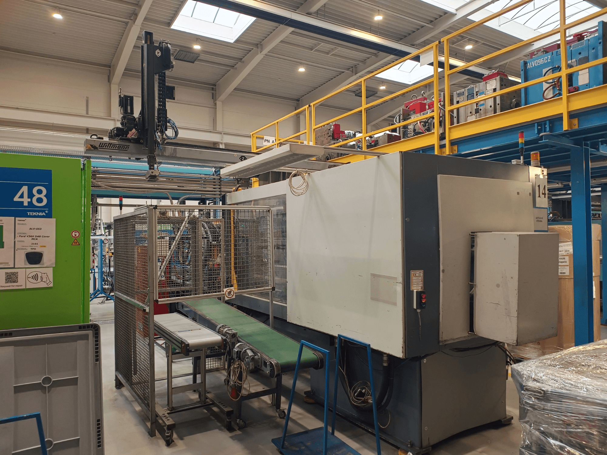 Automatyka przemysłowa firmy Winmon, widok z boku przedstawiający przenośnik taśmowy, panel sterowania i klatkę bezpieczeństwa w warunkach fabrycznych.