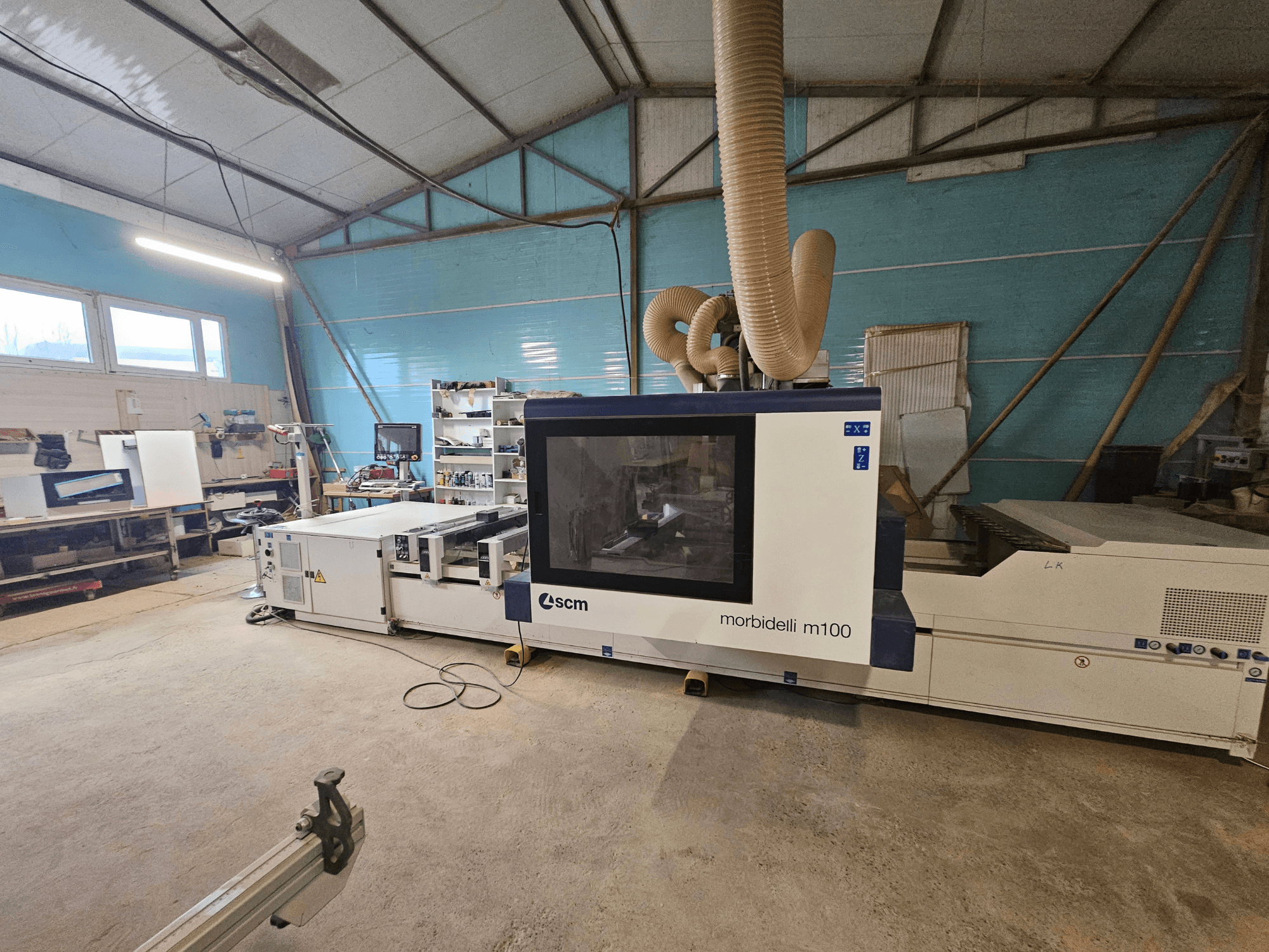 Maszyna CNC SCM Morbidelli M100 w warsztacie, widok z przodu, system odsysania pyłu i panel sterowania.