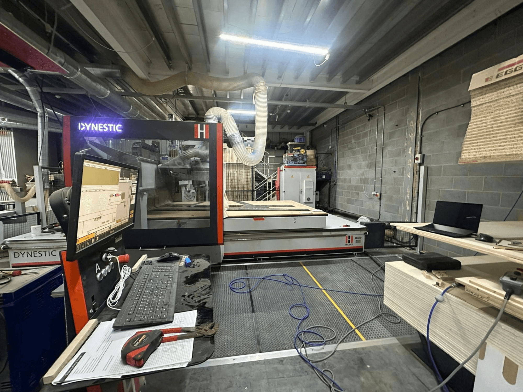 Frezarka do drewna HOLZHER Dynestic 7535 w warsztacie, panel sterowania, monitor i materiały na stole roboczym, widok z przodu.